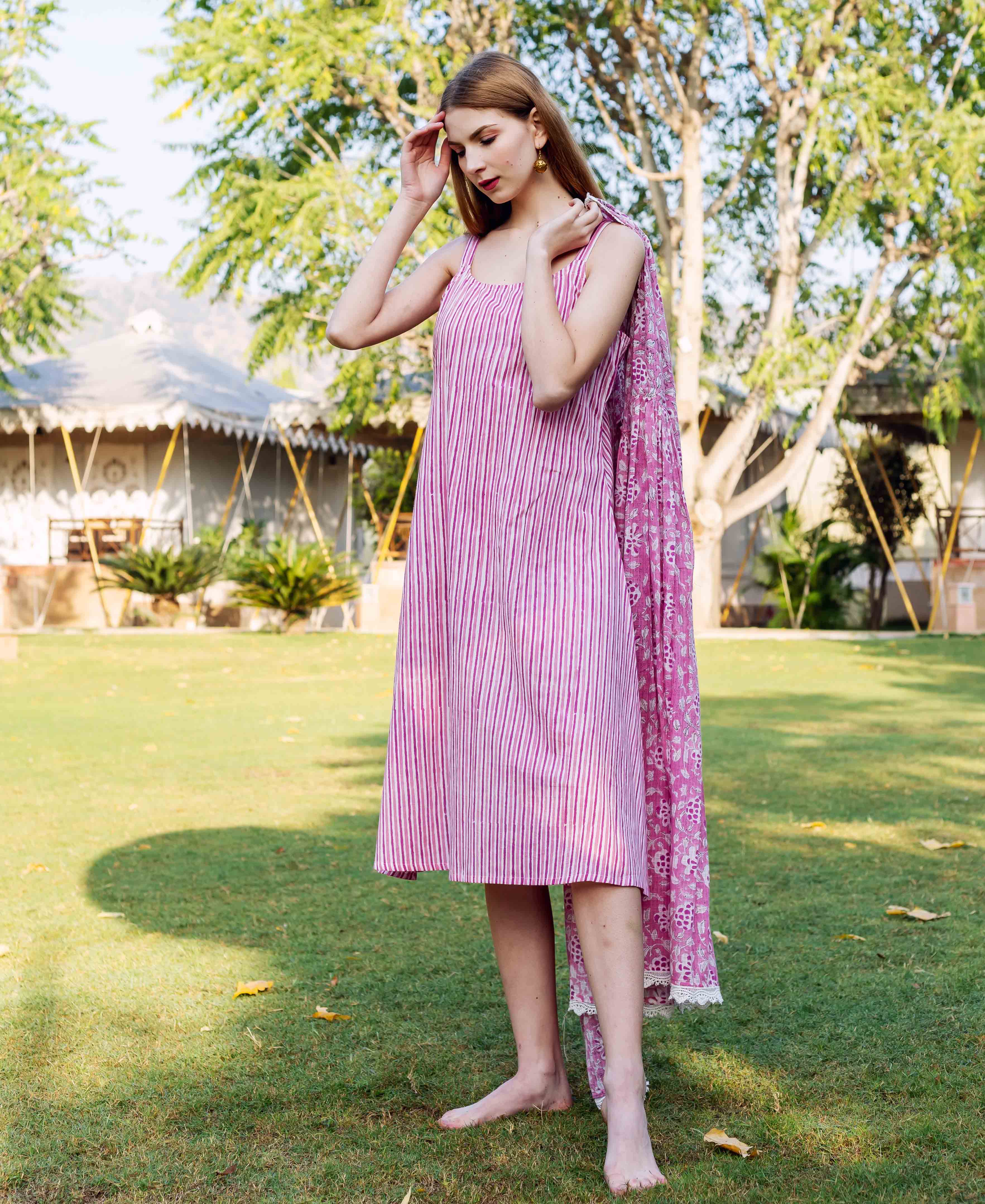 Model in a pink hand-block printed striped dress with a floral printed matching dupatta.
