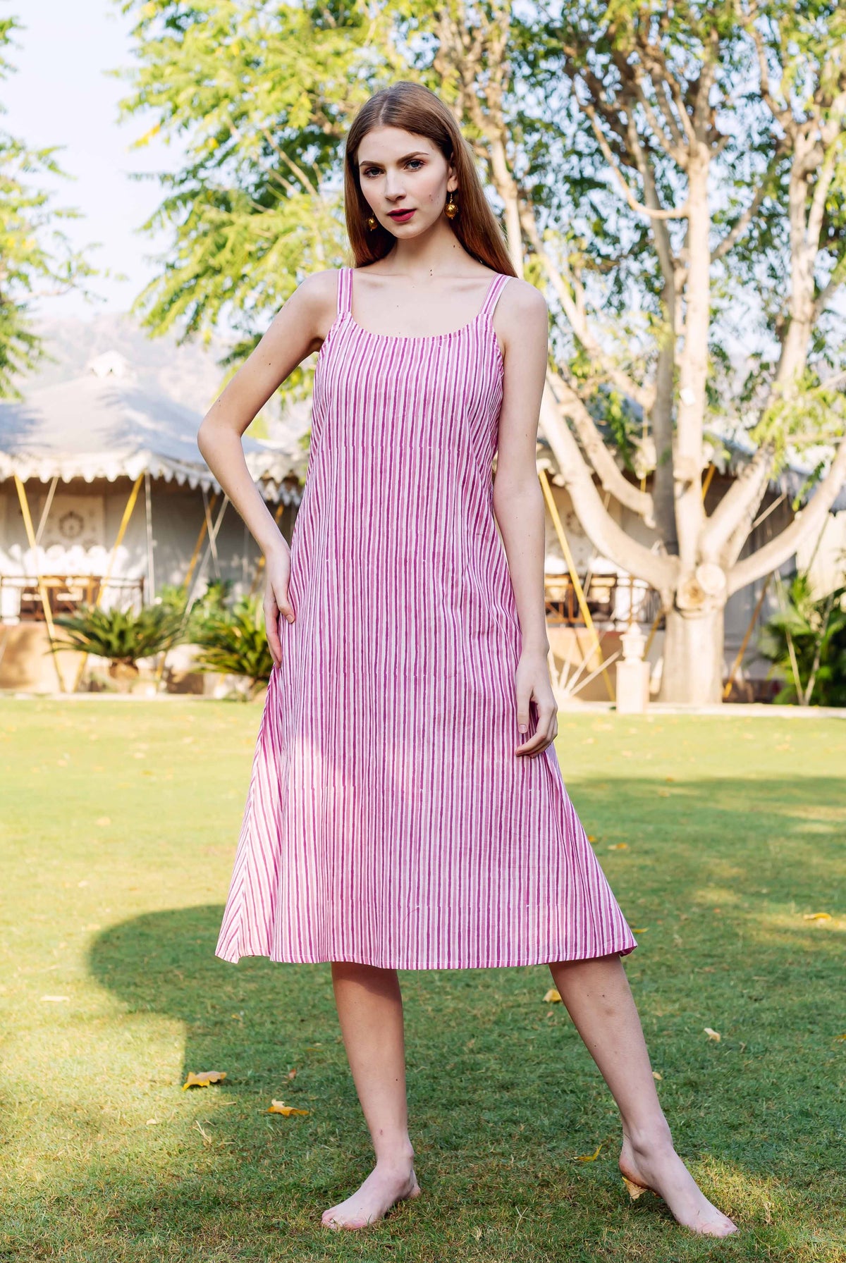 Front view of model in a pink vertically striped sleeveless midi dress.