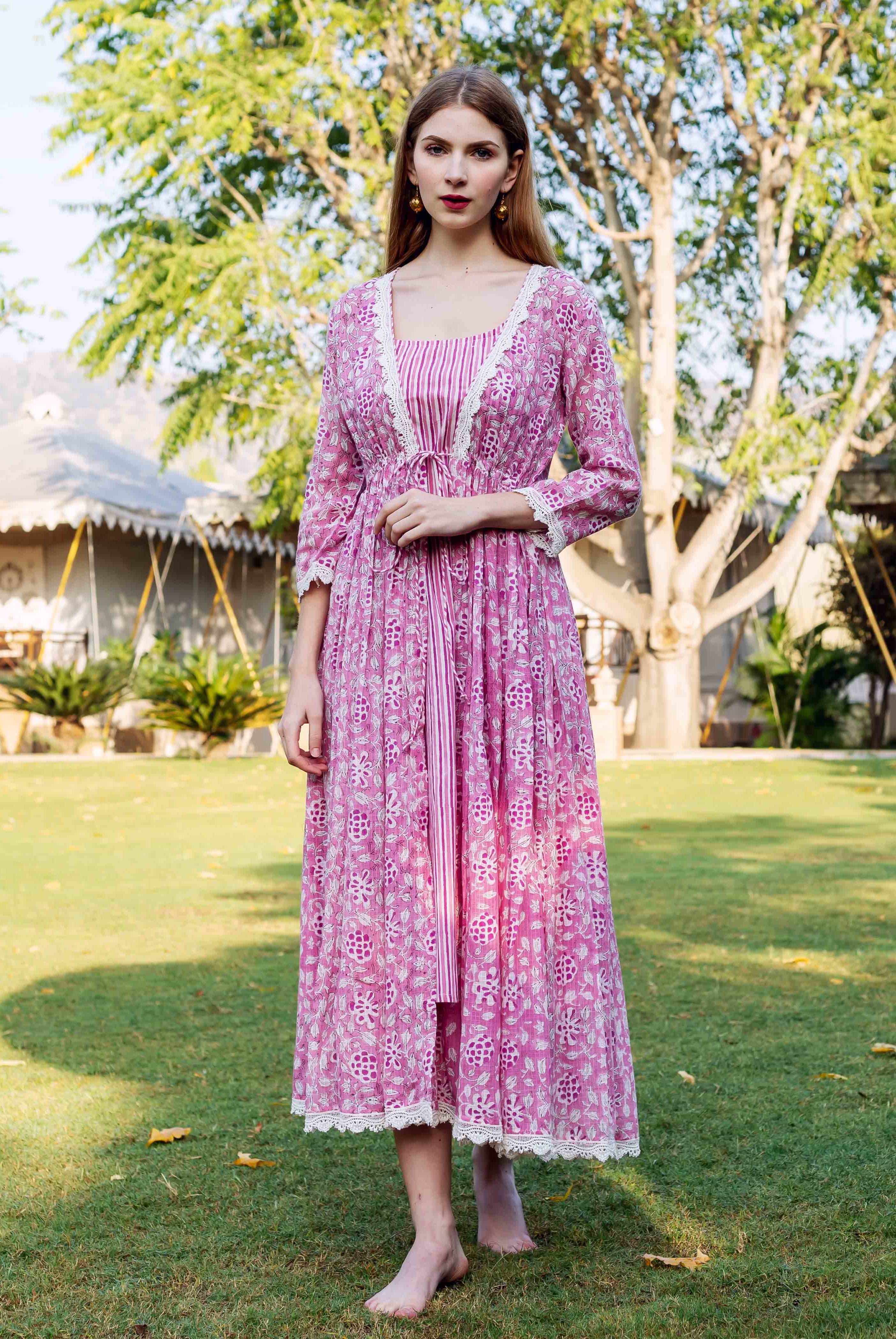 Woman wears a pink hand-block-printed jacket dress with white lace trim and vertical stripes.