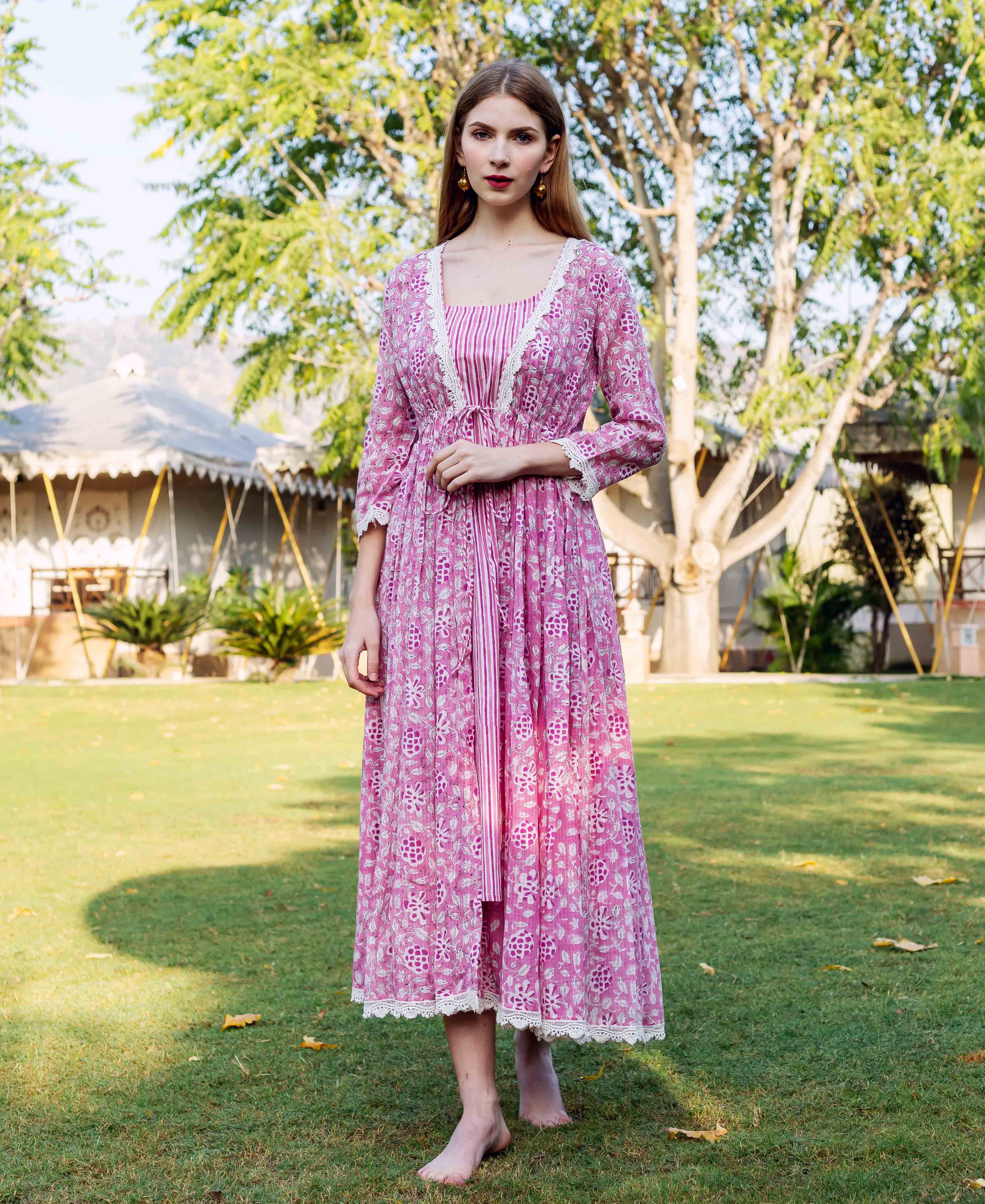 Woman wears a pink hand-block-printed jacket dress with white lace trim and vertical stripes.