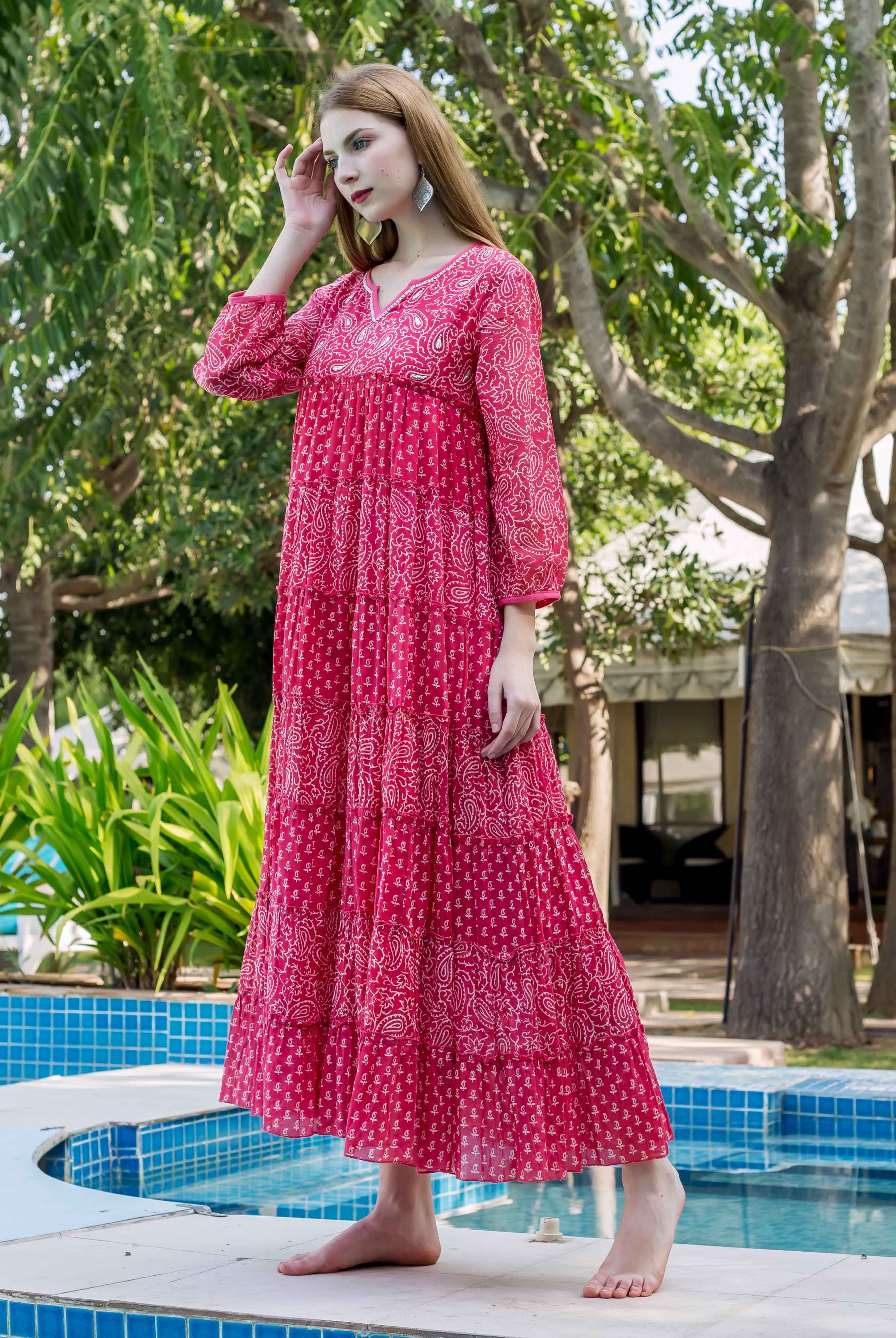 Model wears a deep pink embroidered tiered maxi dress with white paisley print.