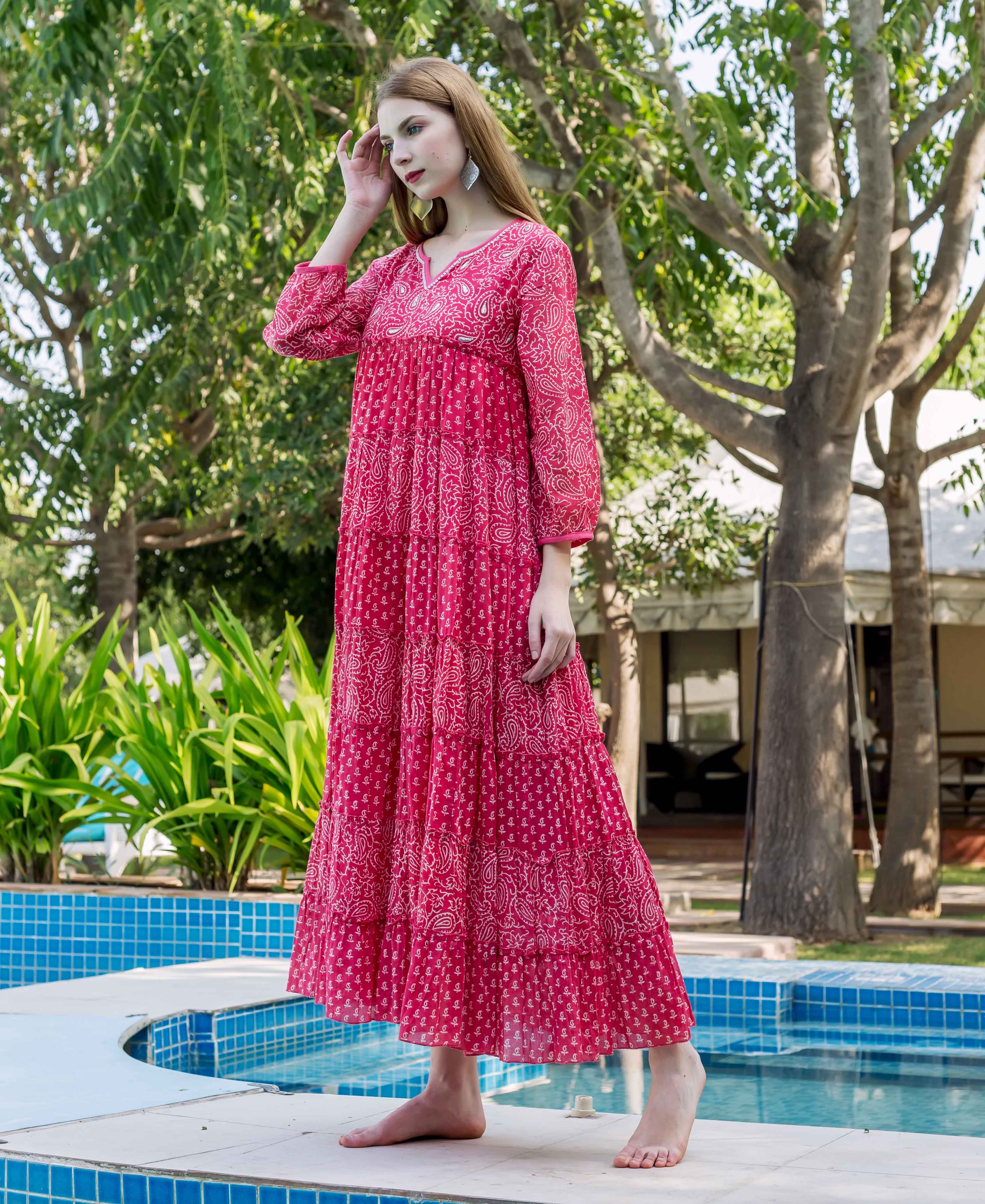 Model wears a deep pink embroidered tiered maxi dress with white paisley print.