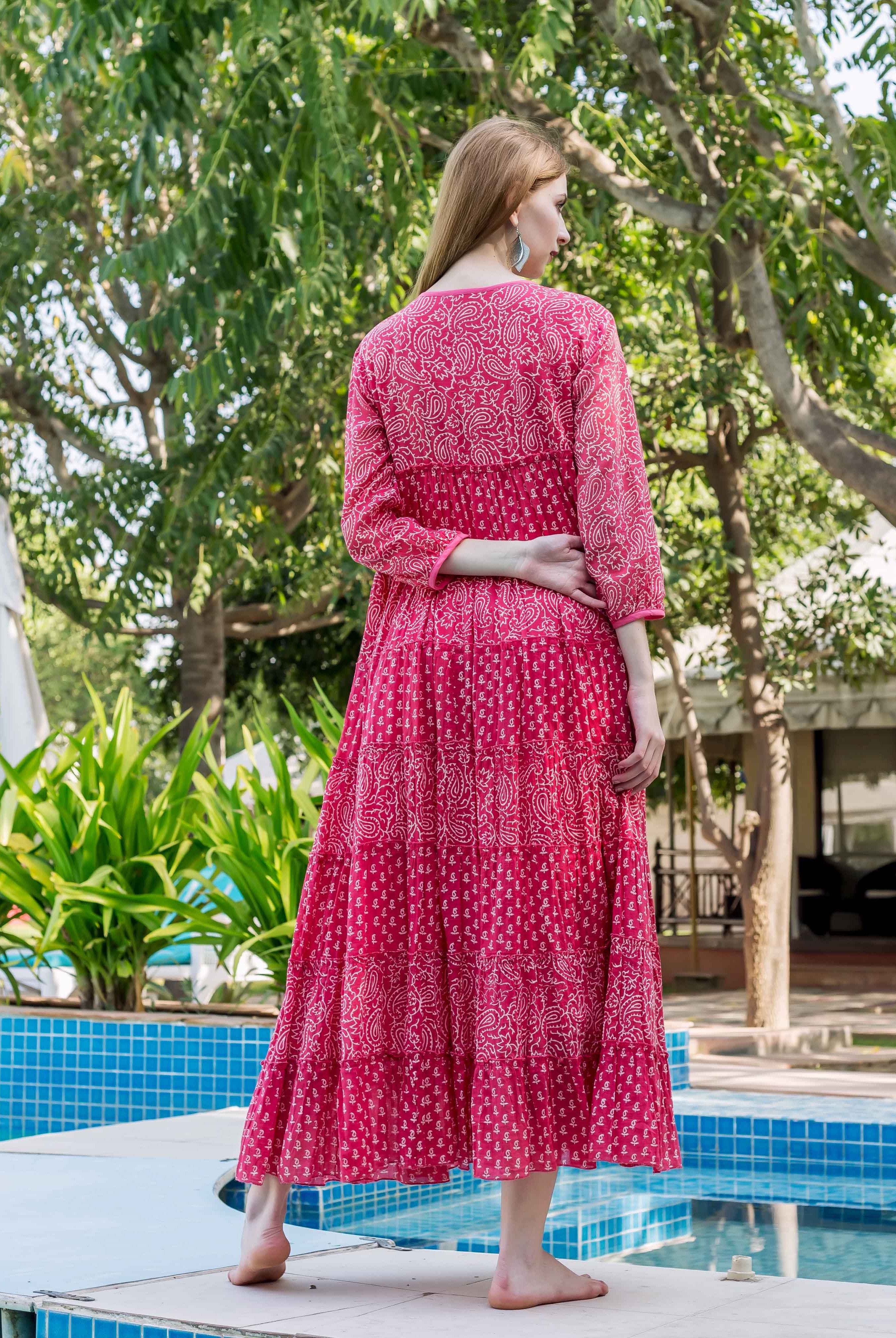 Rear view of model in a pink tiered dress with white block-printed paisley designs.