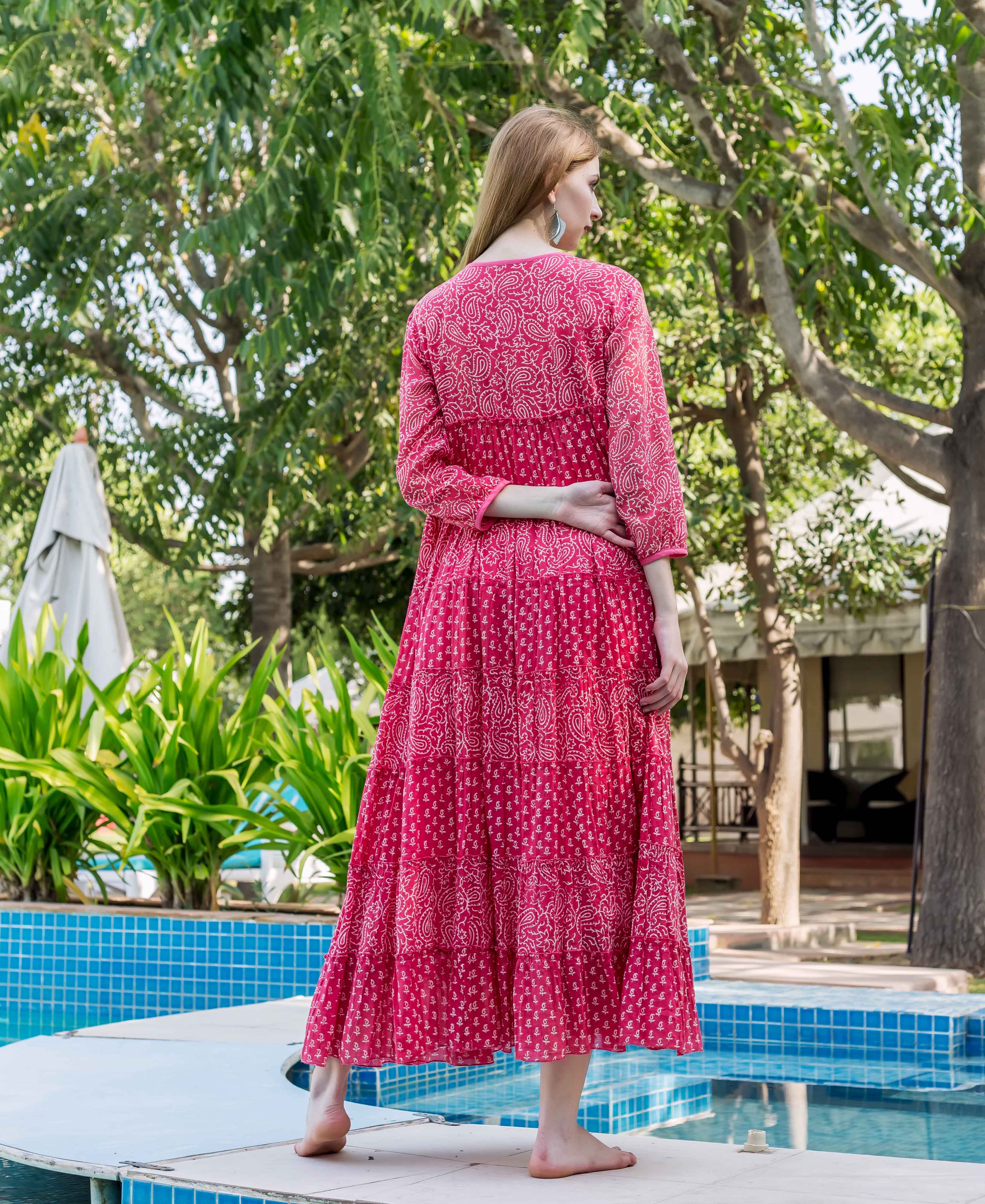 Rear view of model in a pink tiered dress with white block-printed paisley designs.
