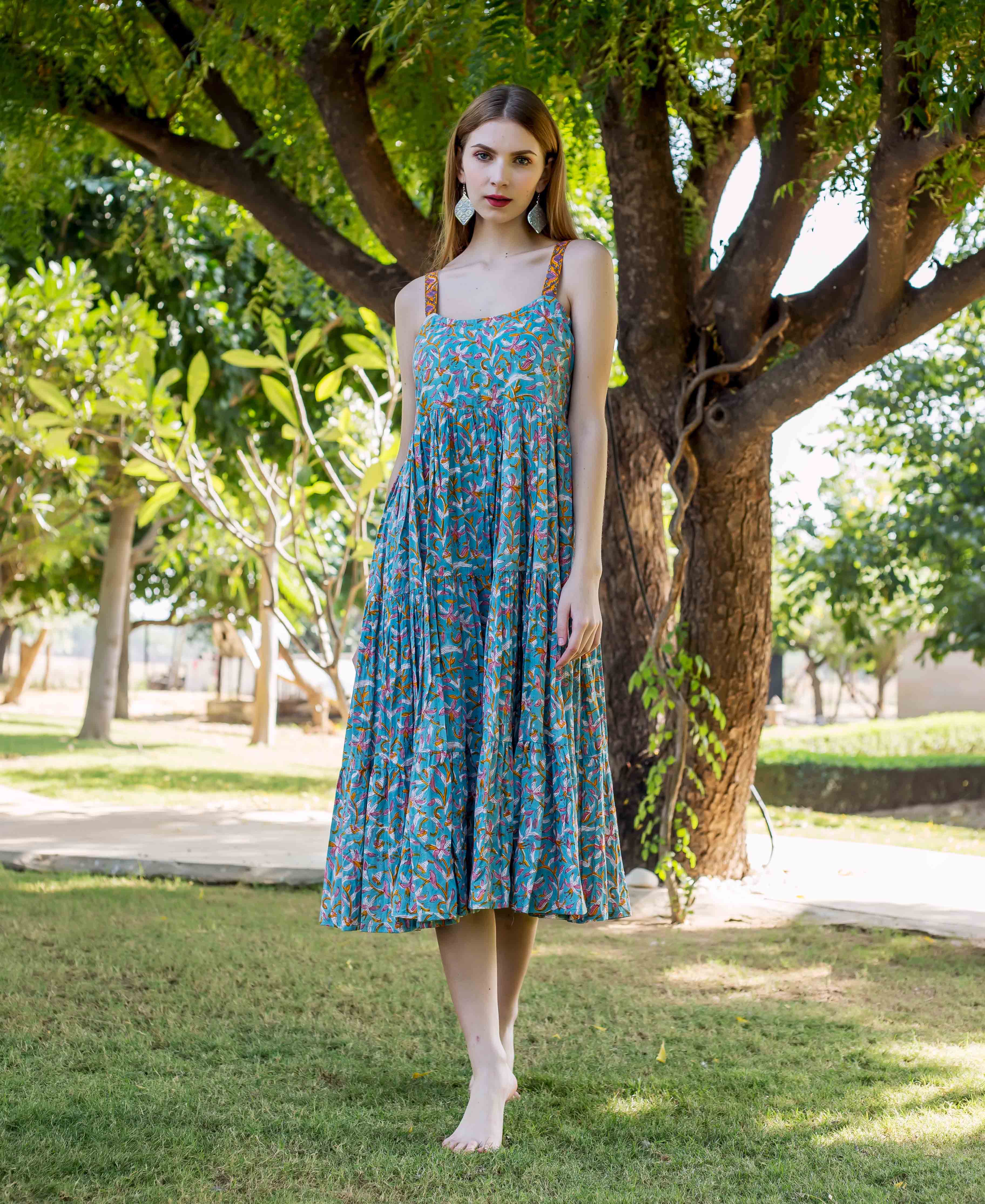 Front view model wearing teal hand-block-printed tiered midi dress with colorful bird and floral motifs.