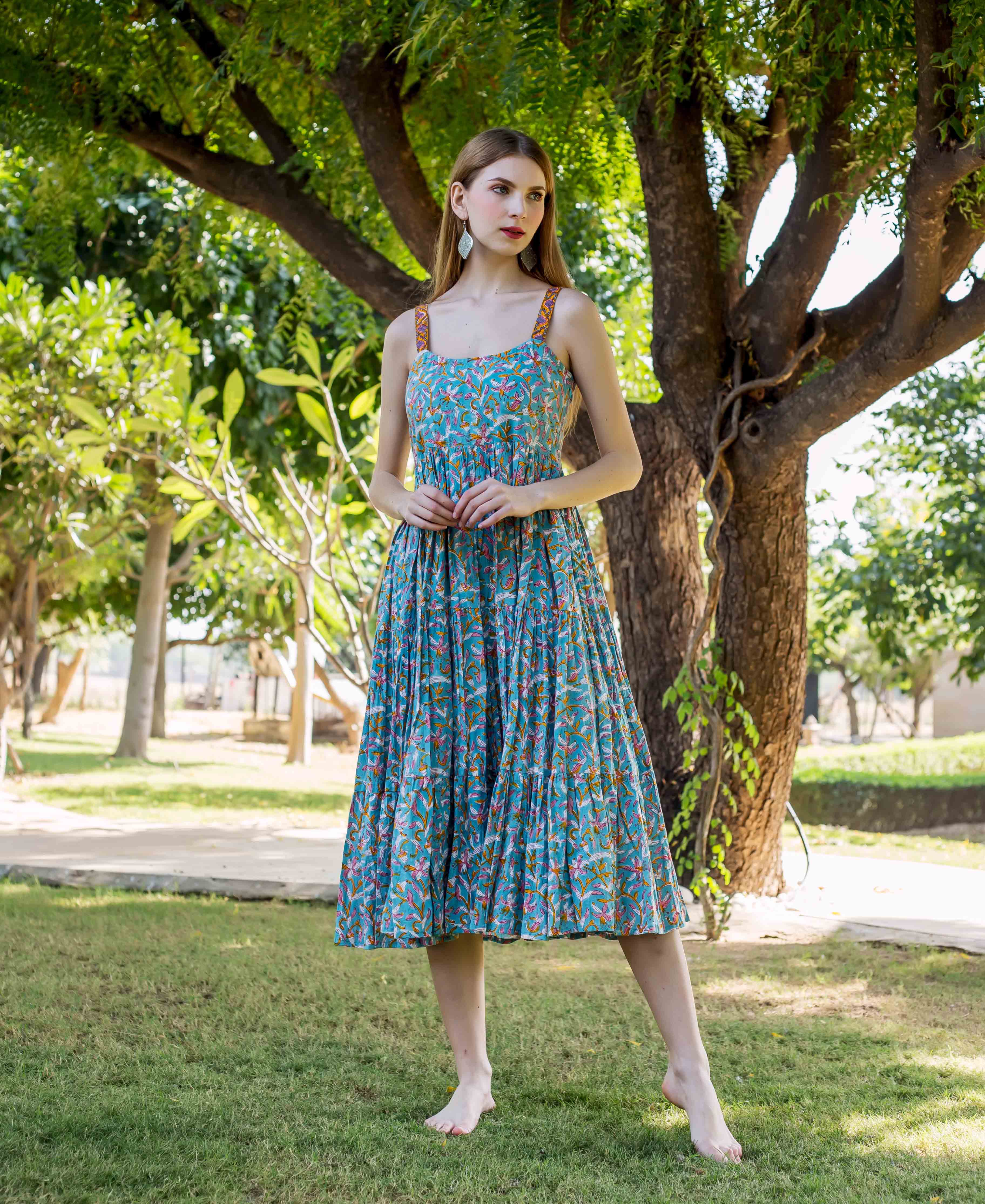 A model wearing a blue, floral-printed dress with thin straps.