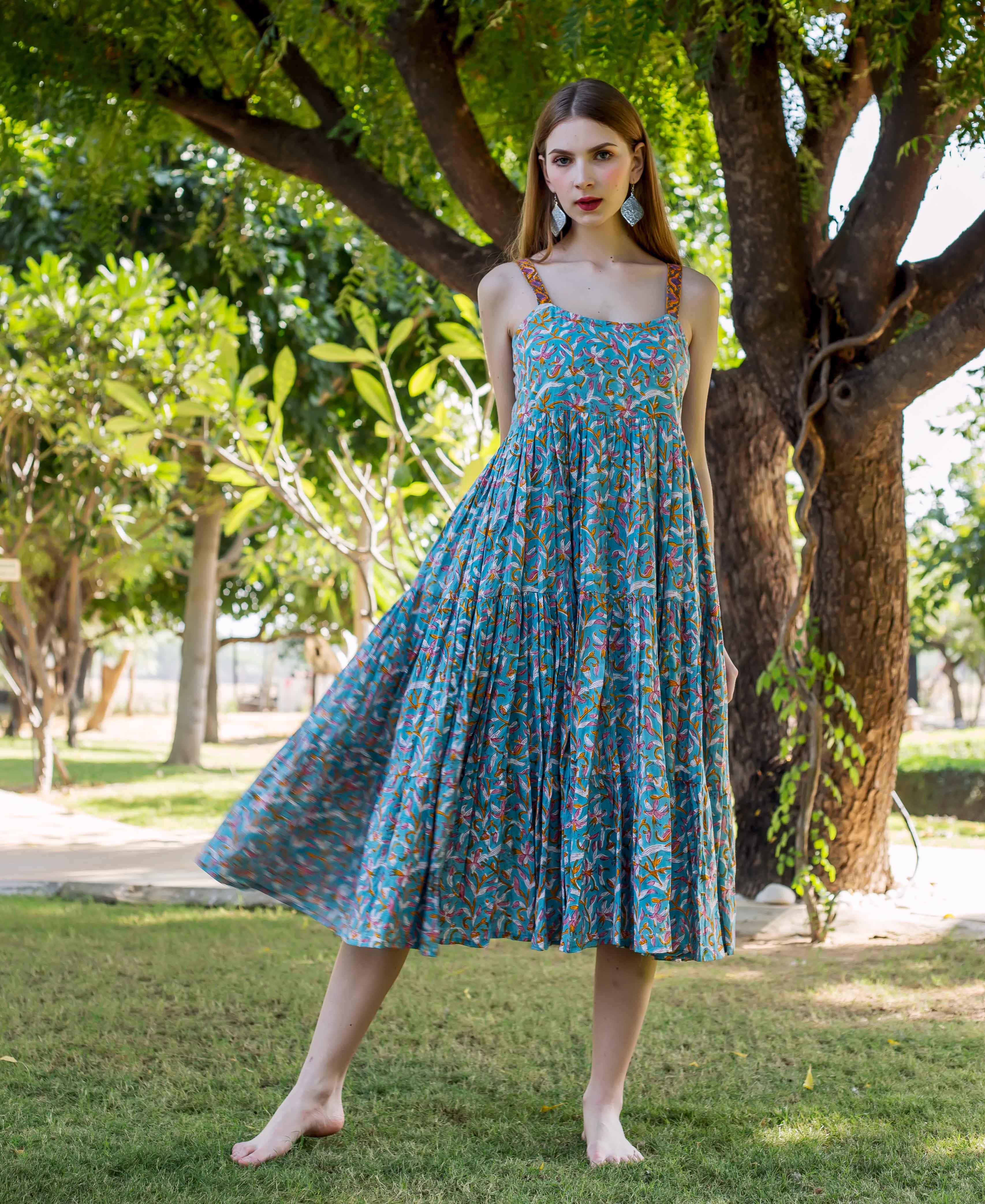 Model in blue hand-block printed tiered midi dress with orange and pink ethnic print.