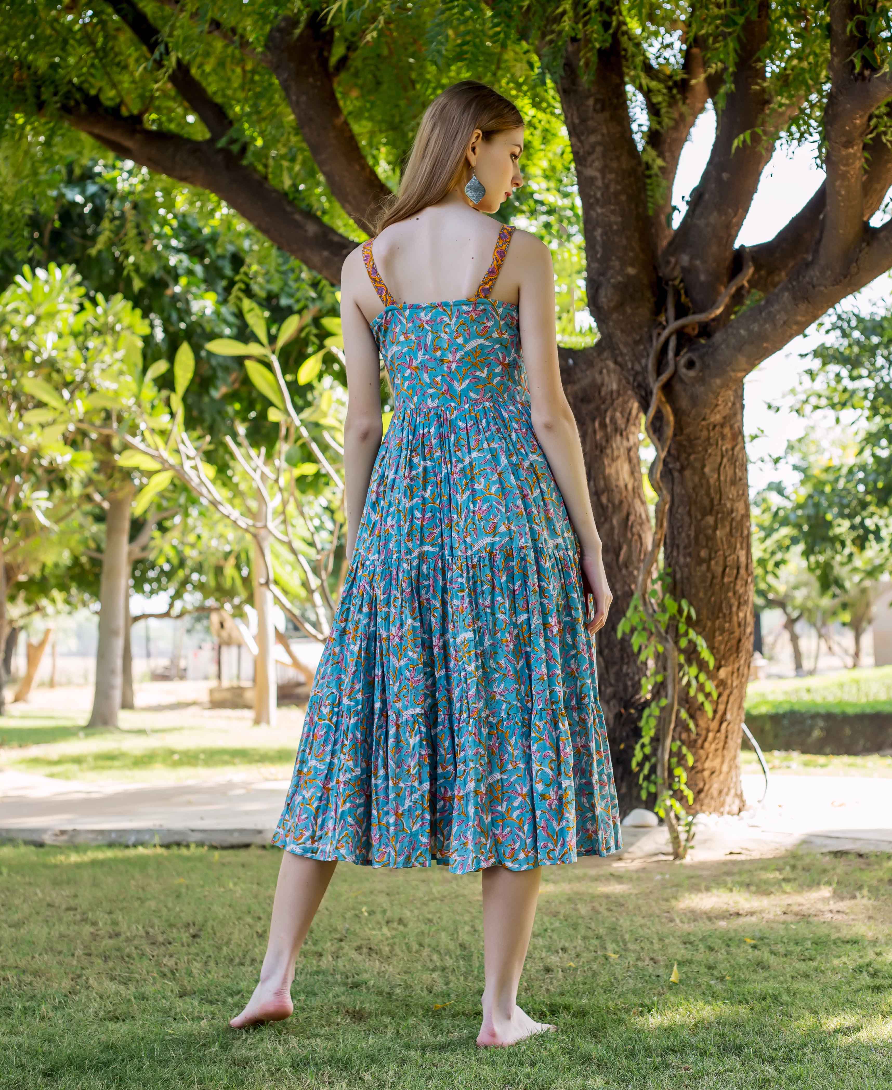 Back view of model in blue tiered hand-block printed dress with colorful ethnic print.