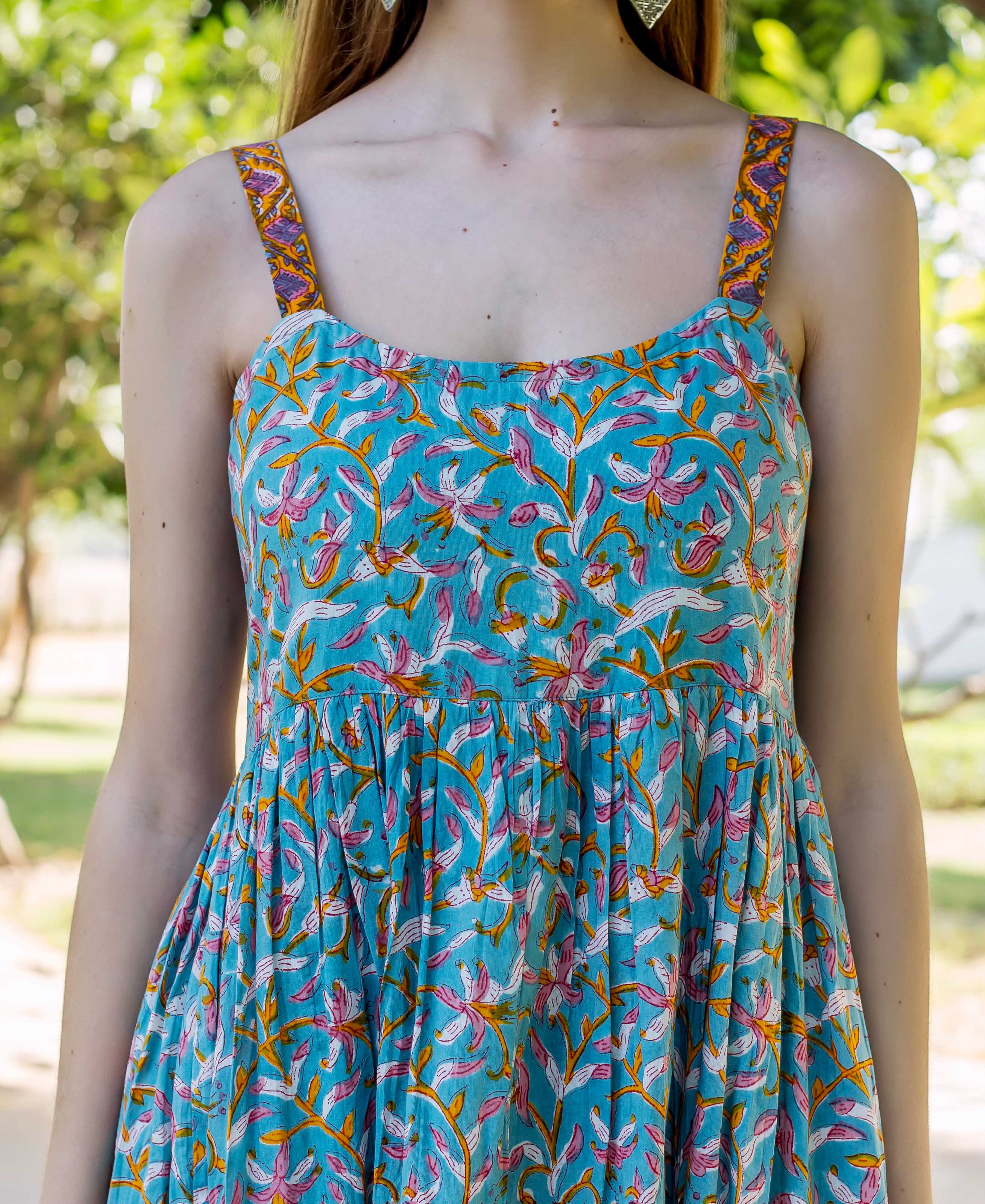 Front view of model in a blue dress with pink, orange floral print and ornate straps.