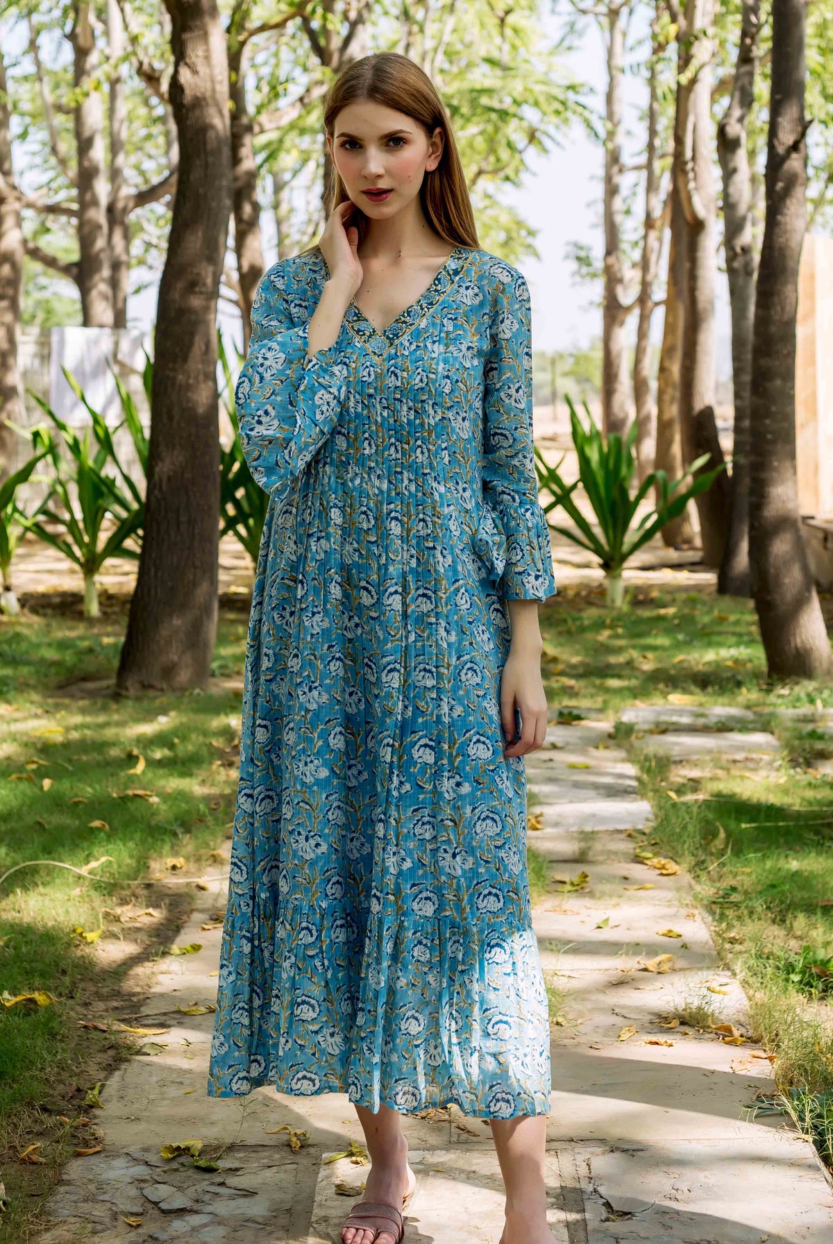 Front view model in blue hand-block-printed floral maxi dress with pleated bodice.