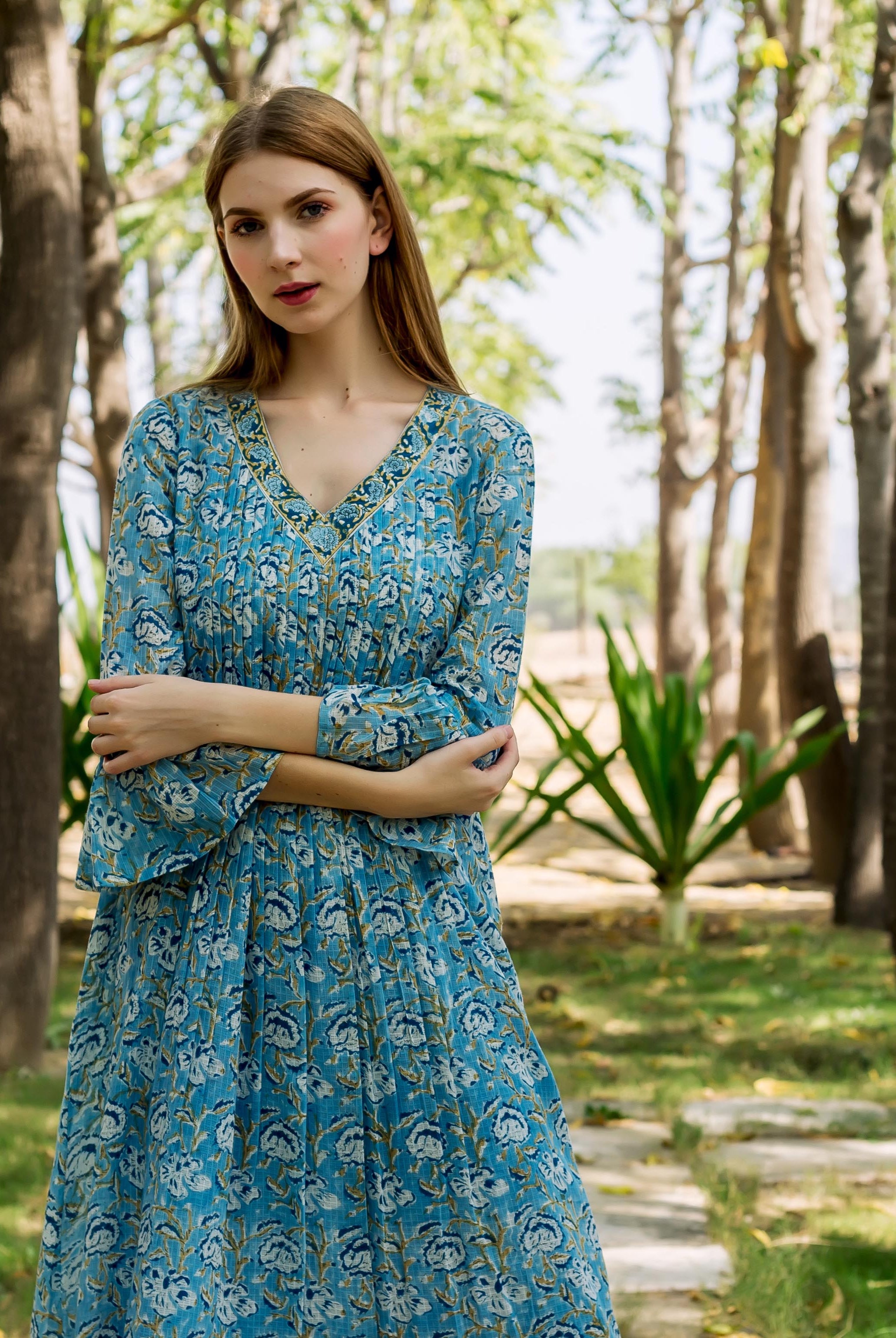 Female model wearing a blue floral hand-block-printed ethnic dress with pleats.