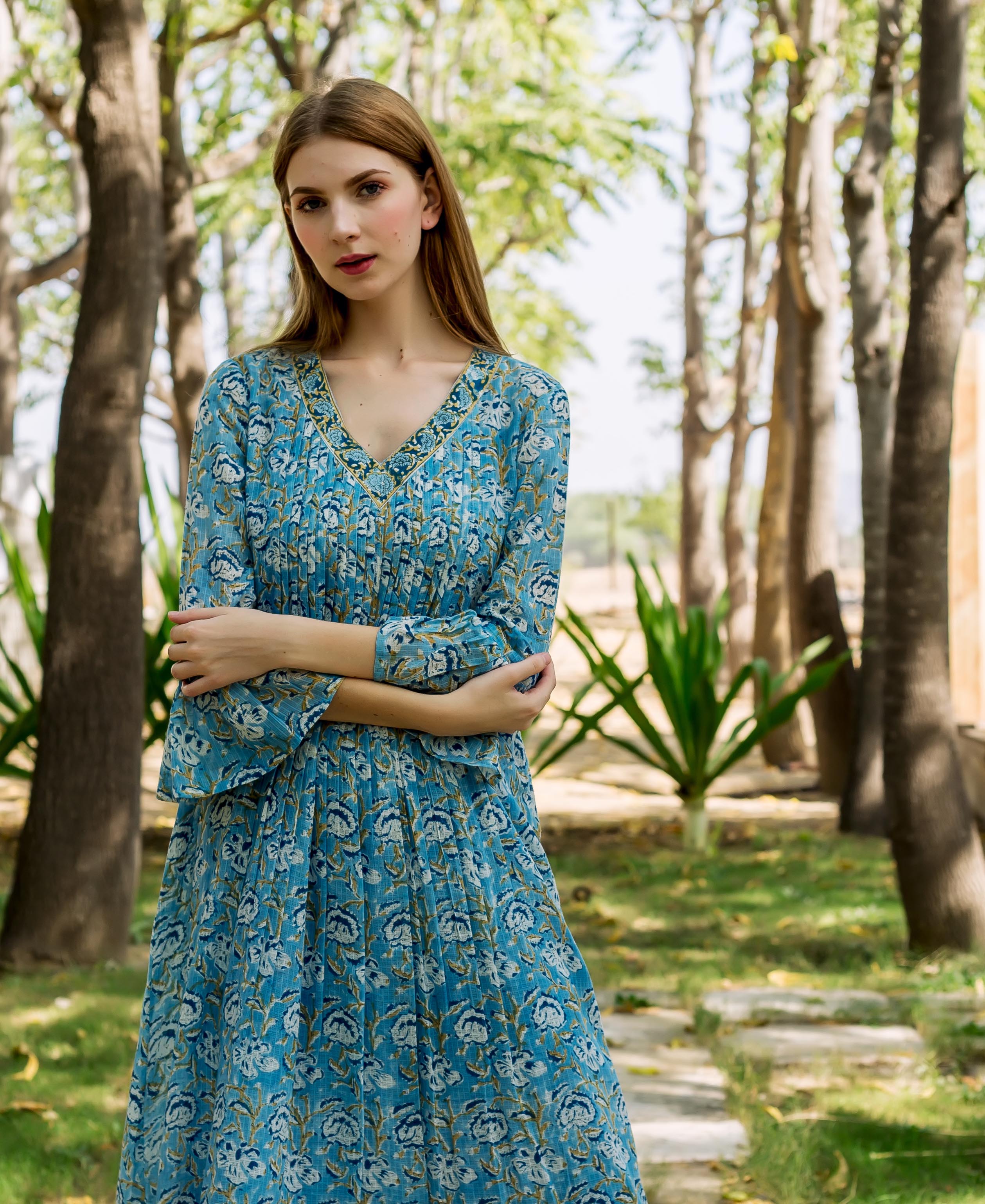 Female model wearing a blue floral hand-block-printed ethnic dress with pleats.