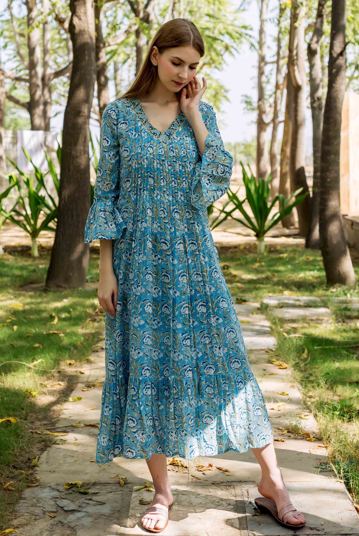 Woman modeling a blue hand-block-printed floral midi dress, front, with pleated bodice.