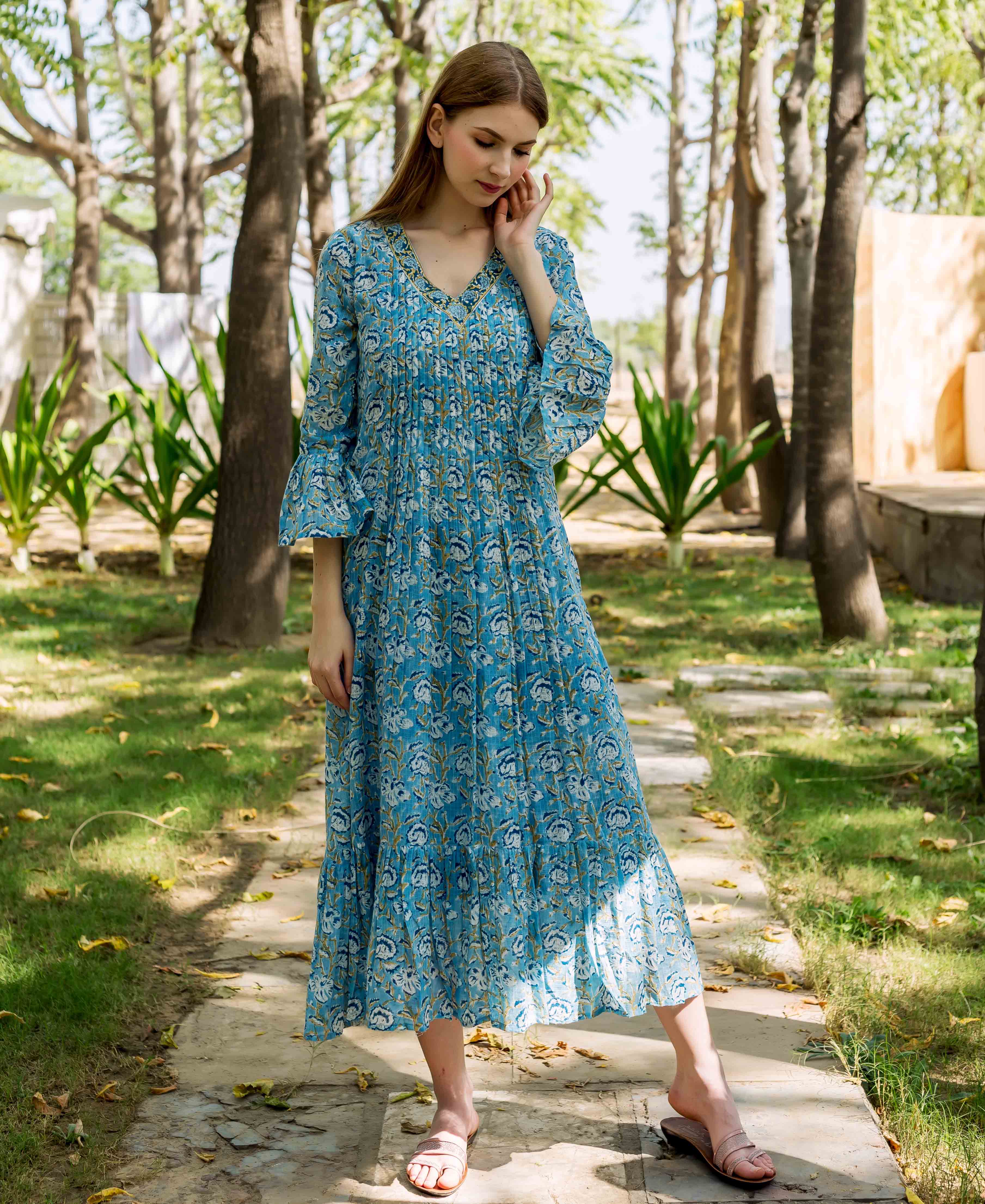 Woman modeling a blue hand-block-printed floral midi dress, front, with pleated bodice.