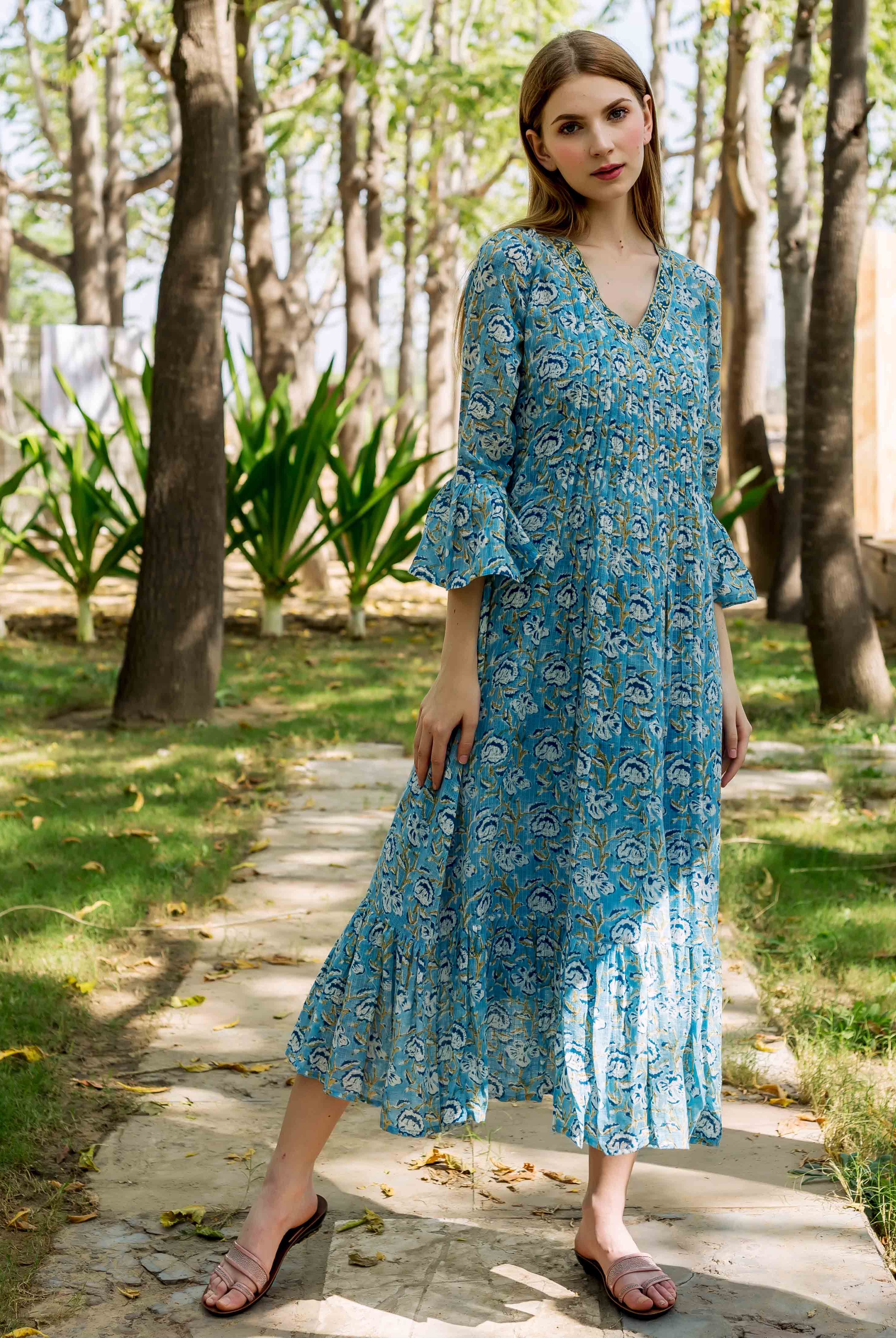 Model wears blue hand-block-printed floral Emily dress with V-neck and bell sleeves.
