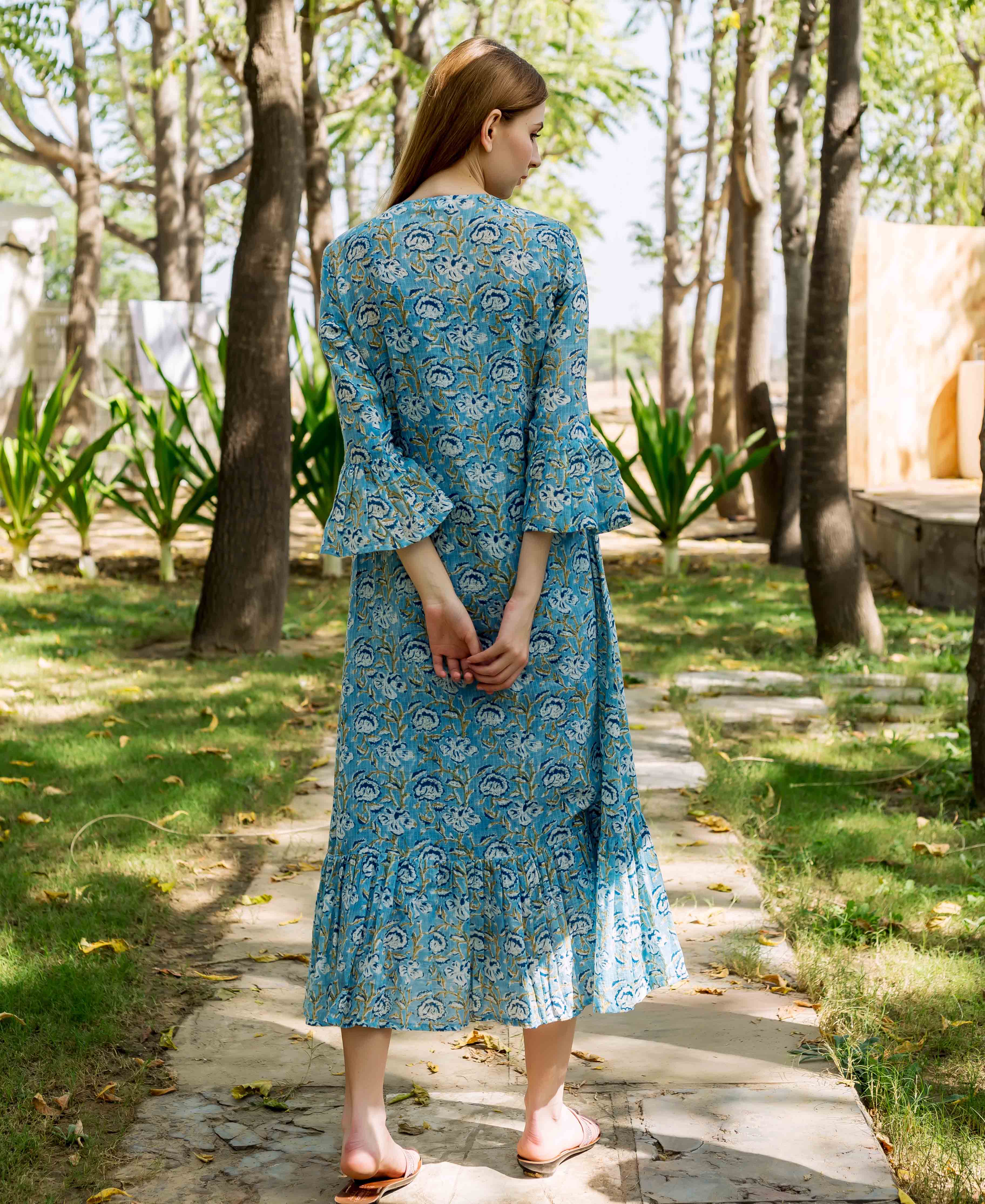 Model's back shows blue floral printed midi dress with bell sleeves and ruffled hem.