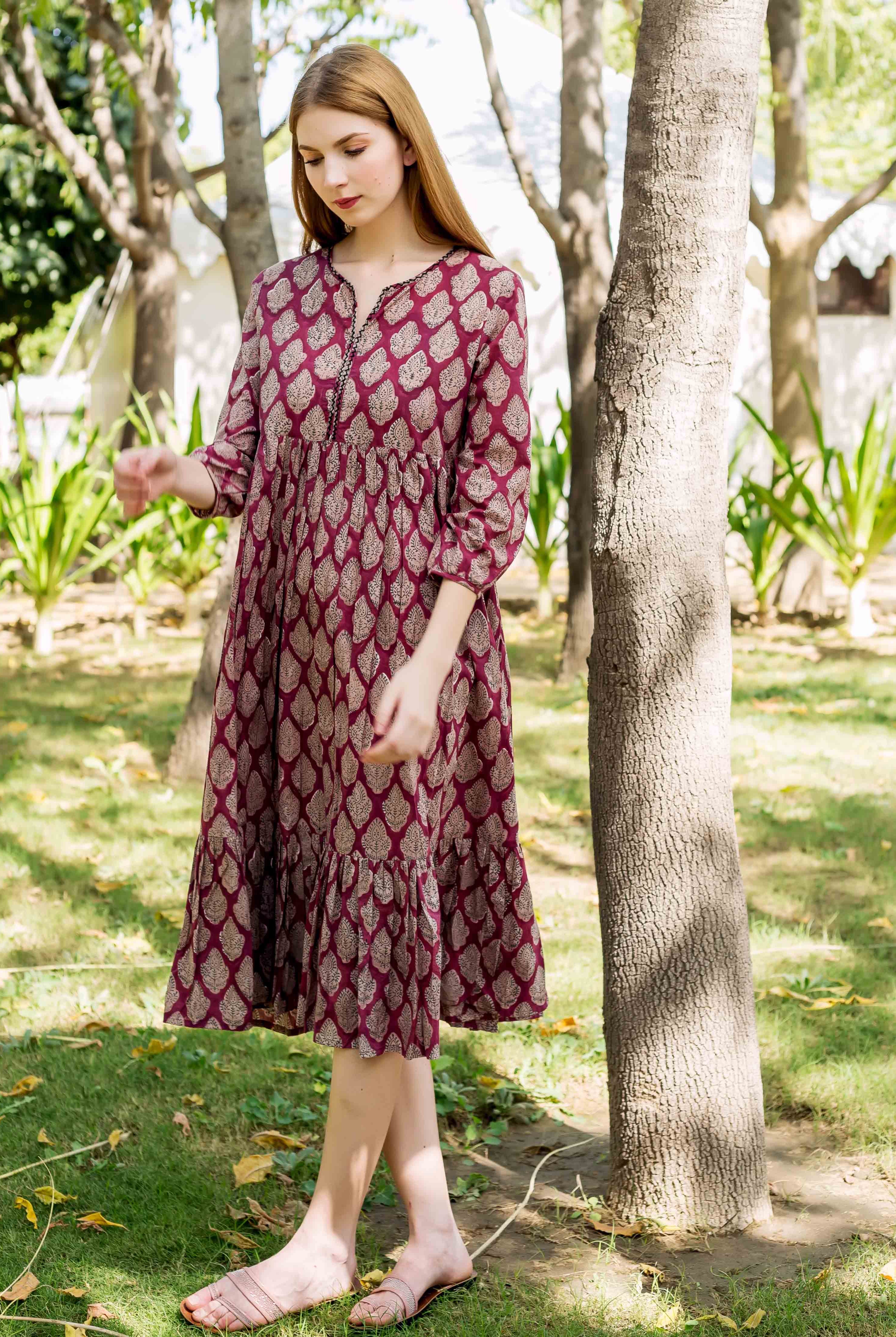 Model wearing a maroon Elizabeth dress with a detailed gold hand-block-printed leaf pattern.