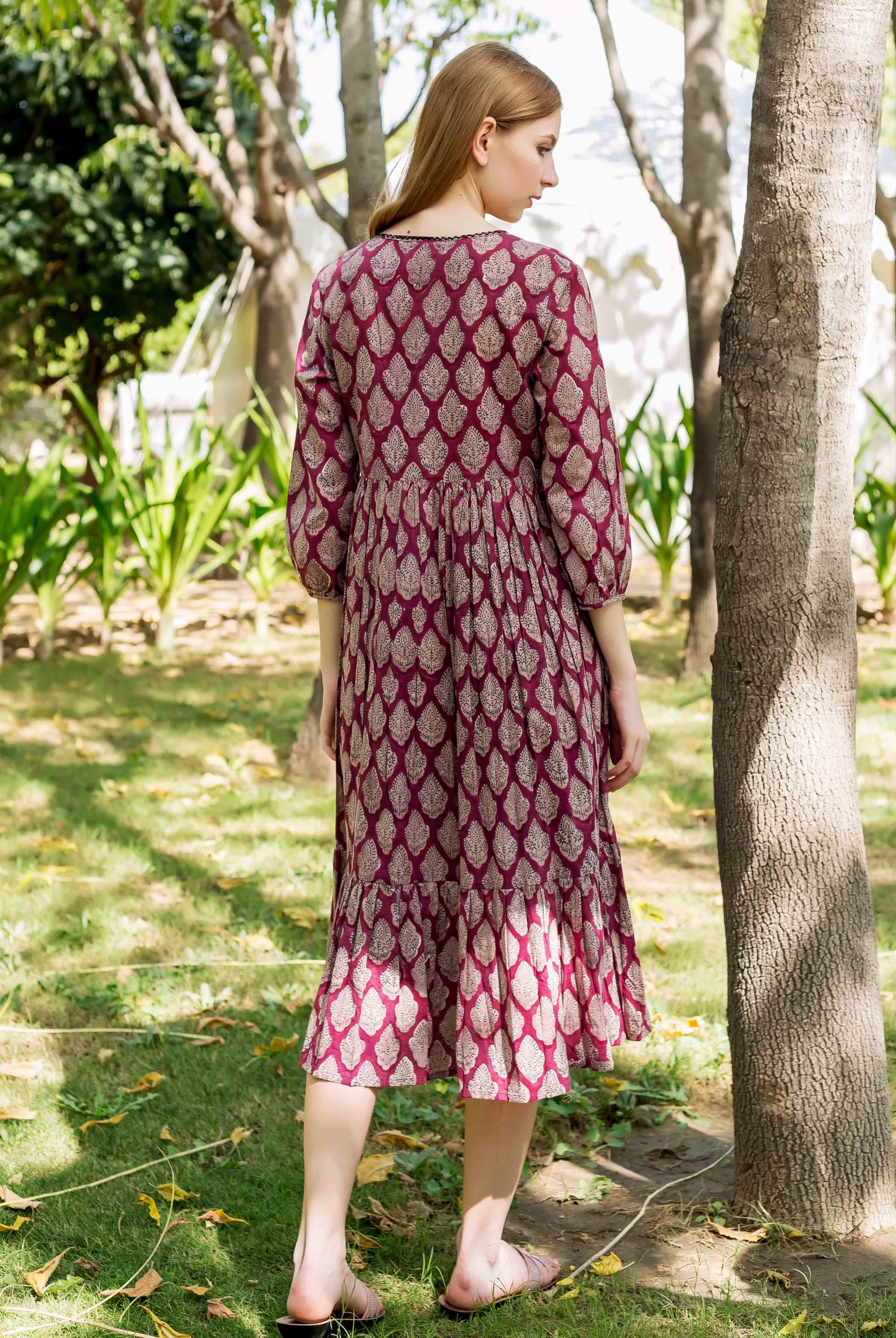 Back view of model in a maroon hand-block-printed dress with intricate leaf patterns.