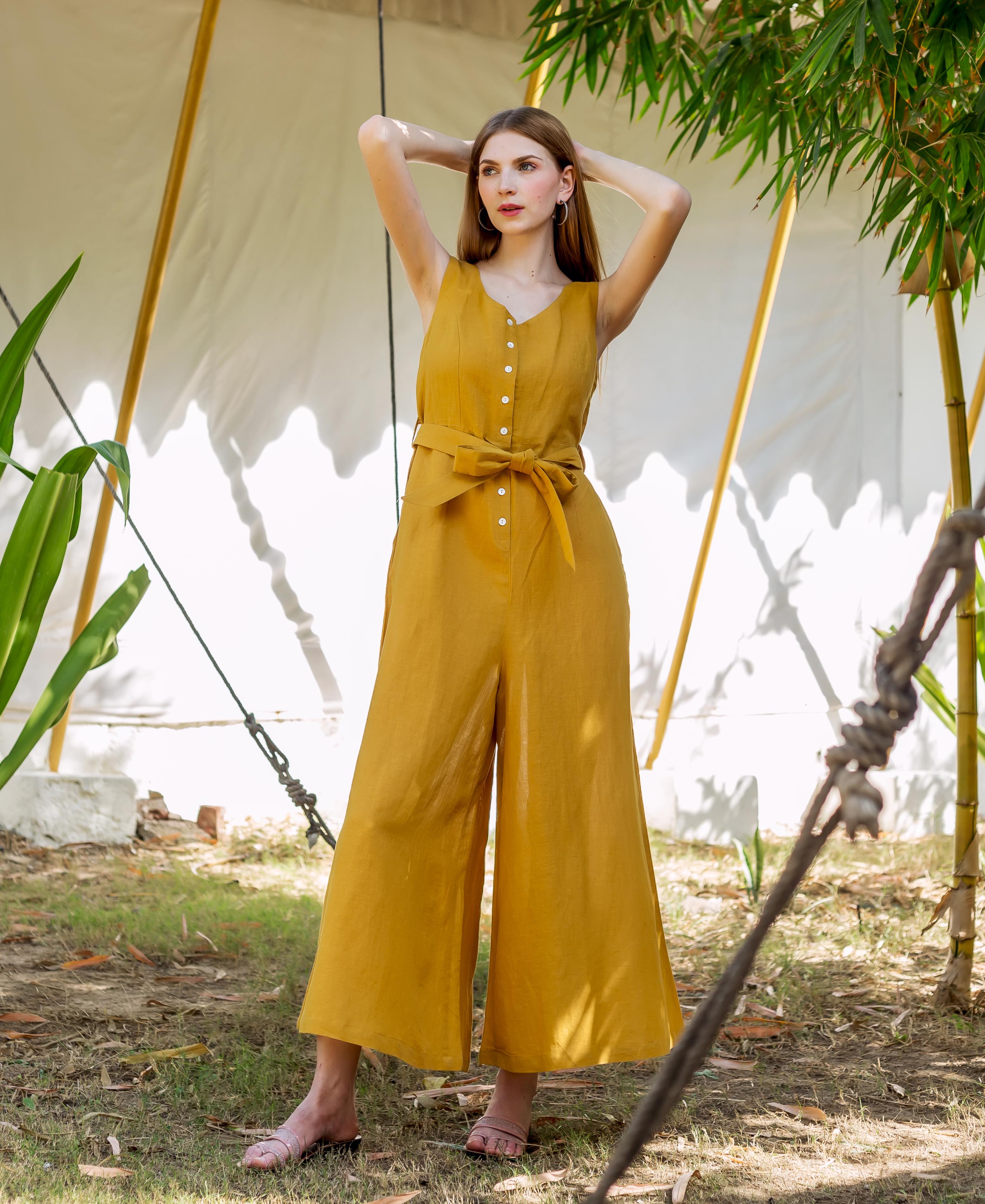Full body, front view of a model wearing an ochre sleeveless button-front tie-waist wide-leg jumpsuit.