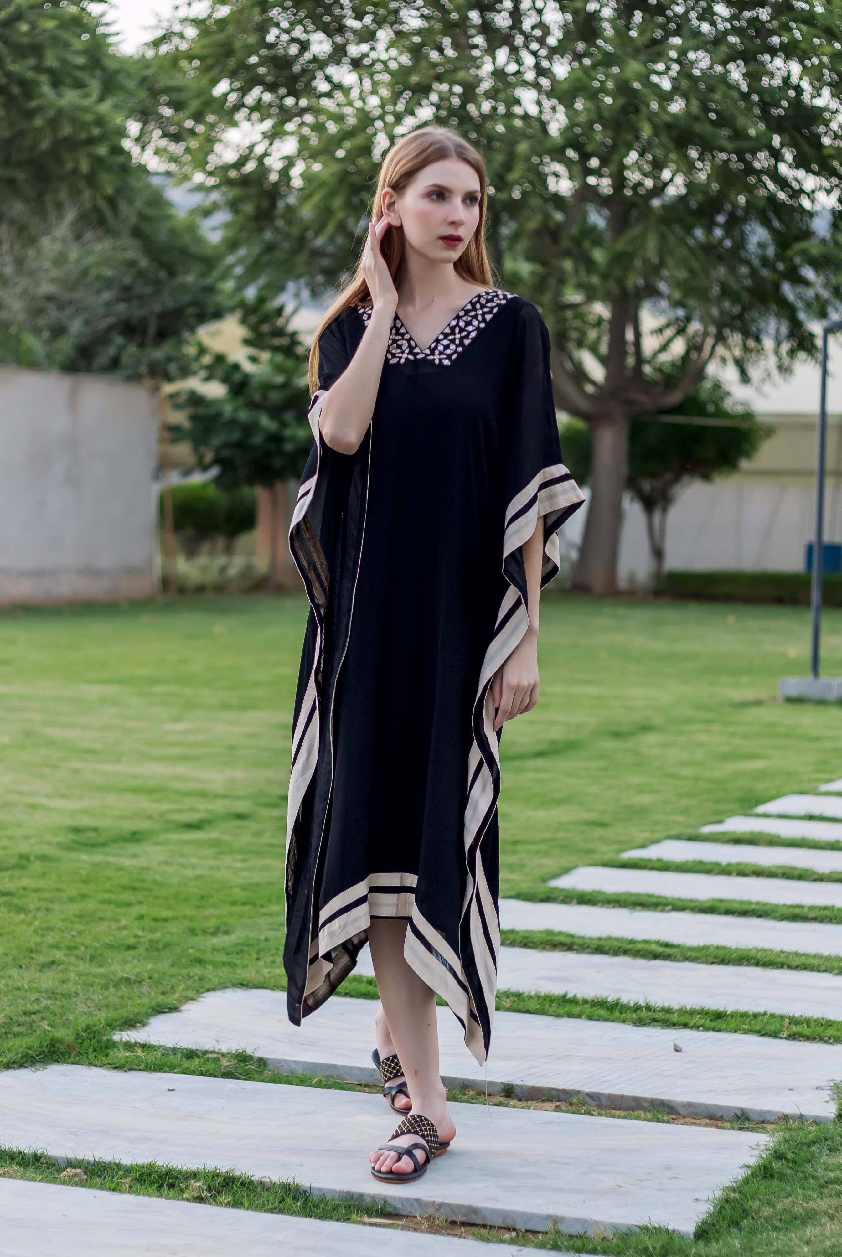 Full look, front, model in black kaftan with embroidered V-neck and hand-block-printed stripes.