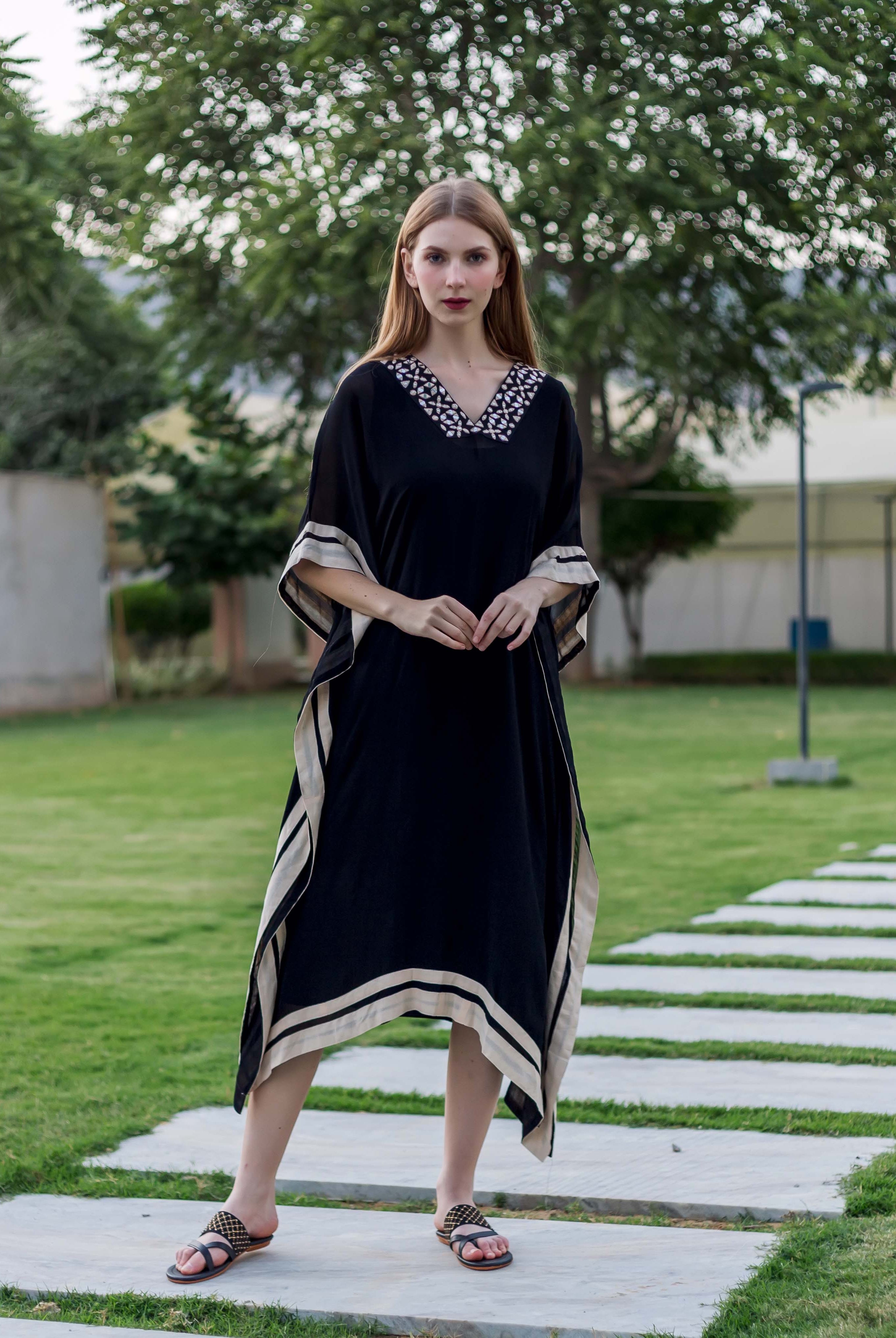 A model wearing a black kaftan with white embroidery and block-printed borders.