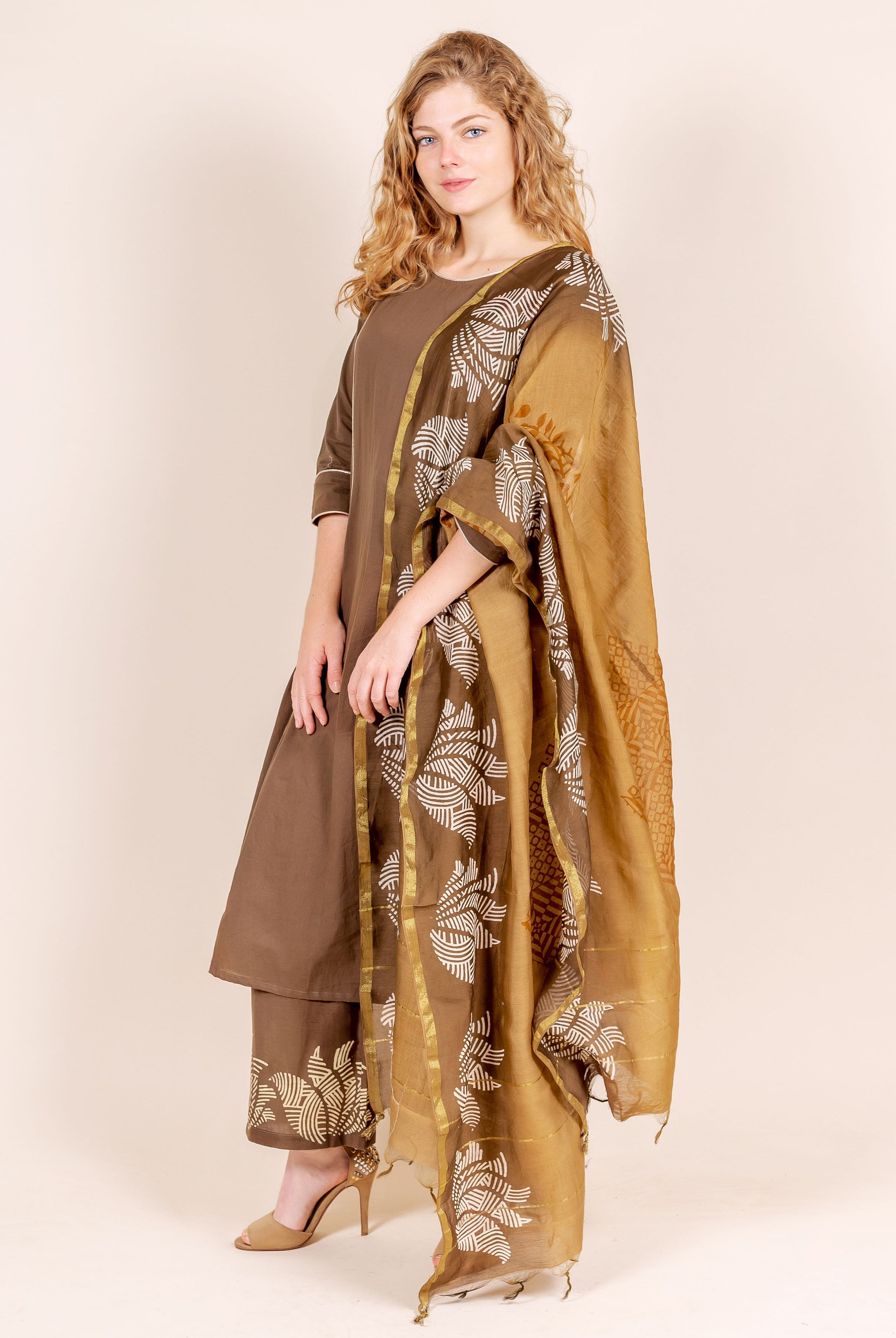 On a model, an angled brown kurta and pants with white hand-block printed beige dupatta.