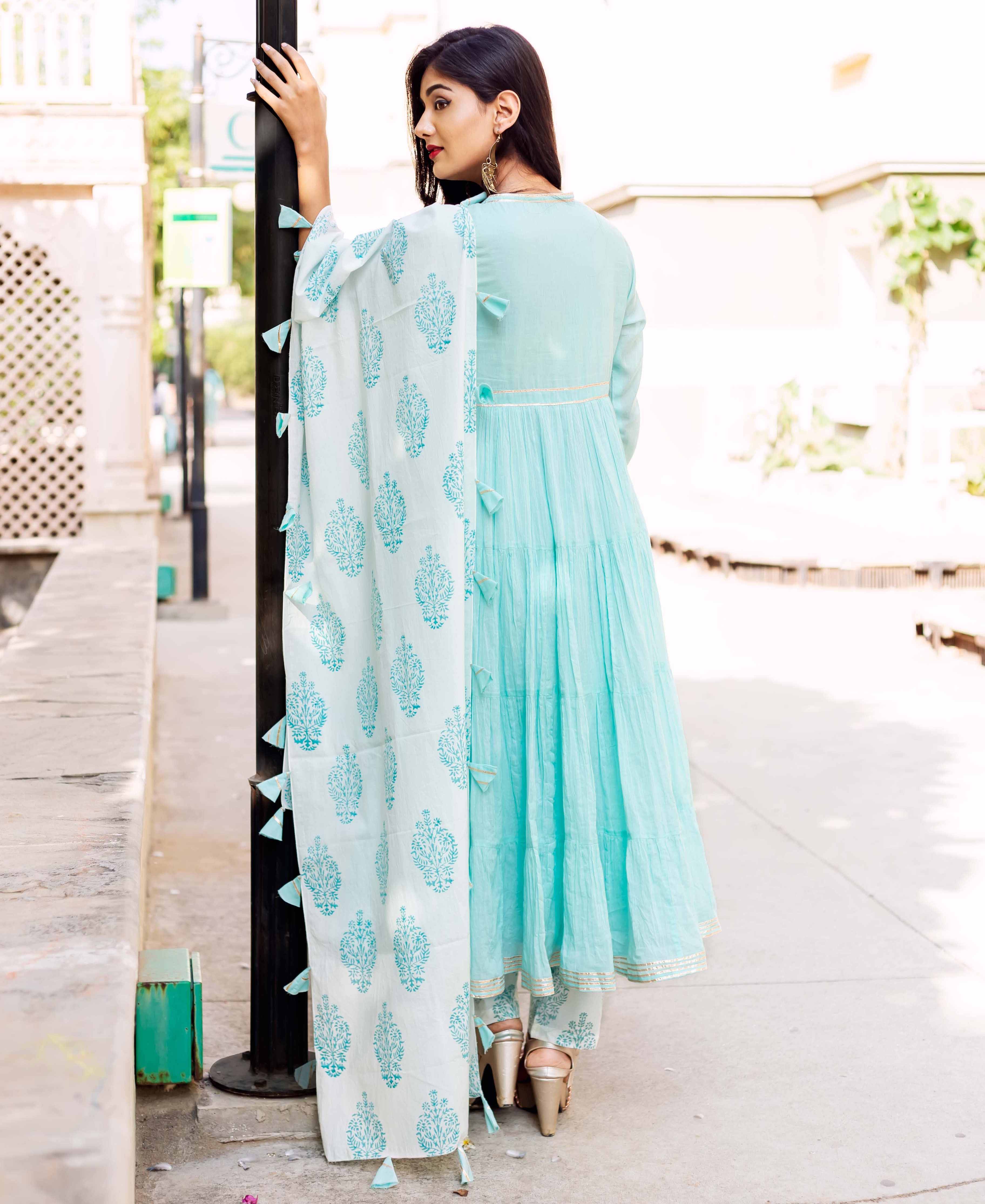 Back view of model in light blue tiered kurta, white block-print dupatta, and printed bottoms.