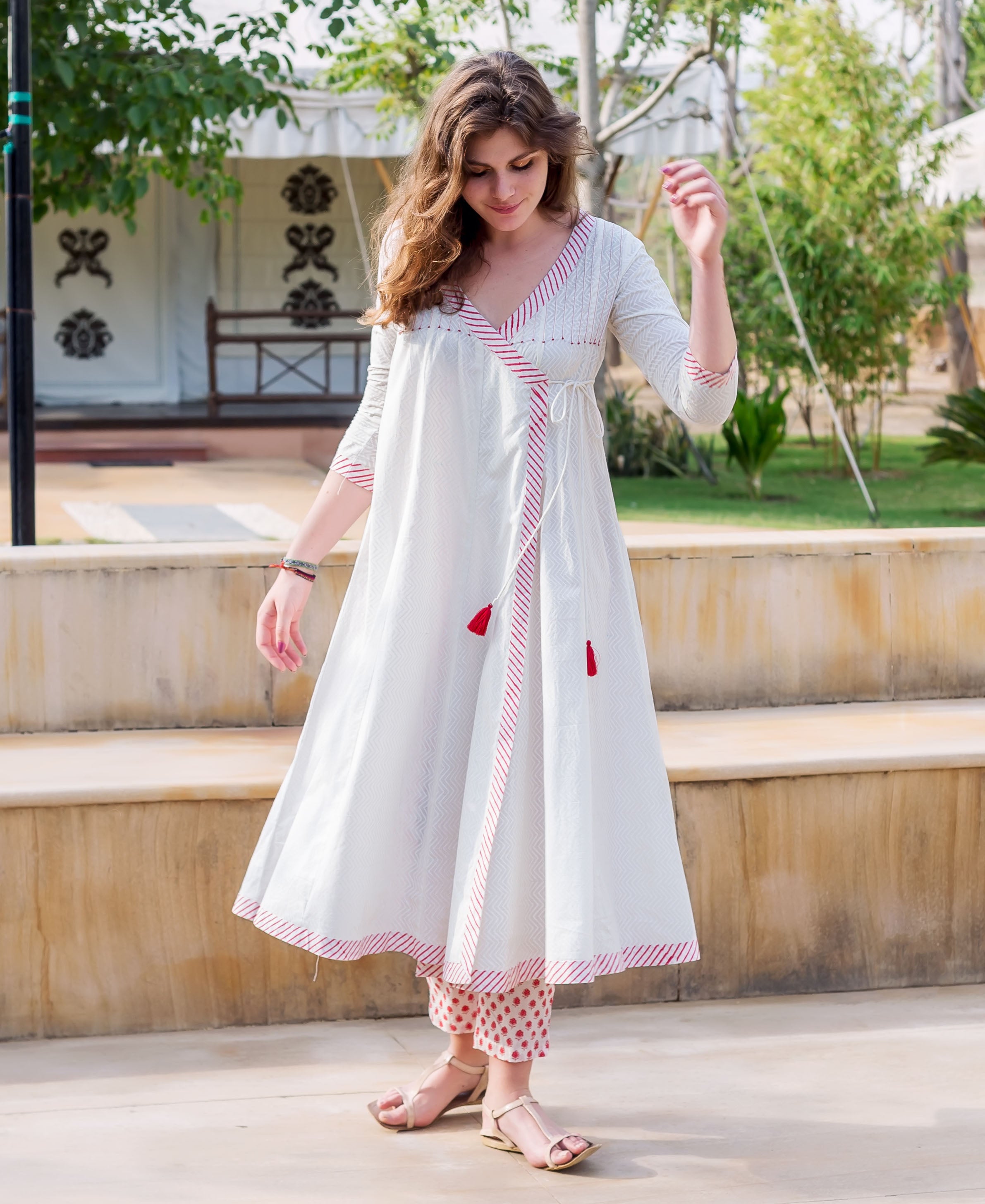 Standing model in white and red Angrakha dress with chevron print, matching polka dot pants.