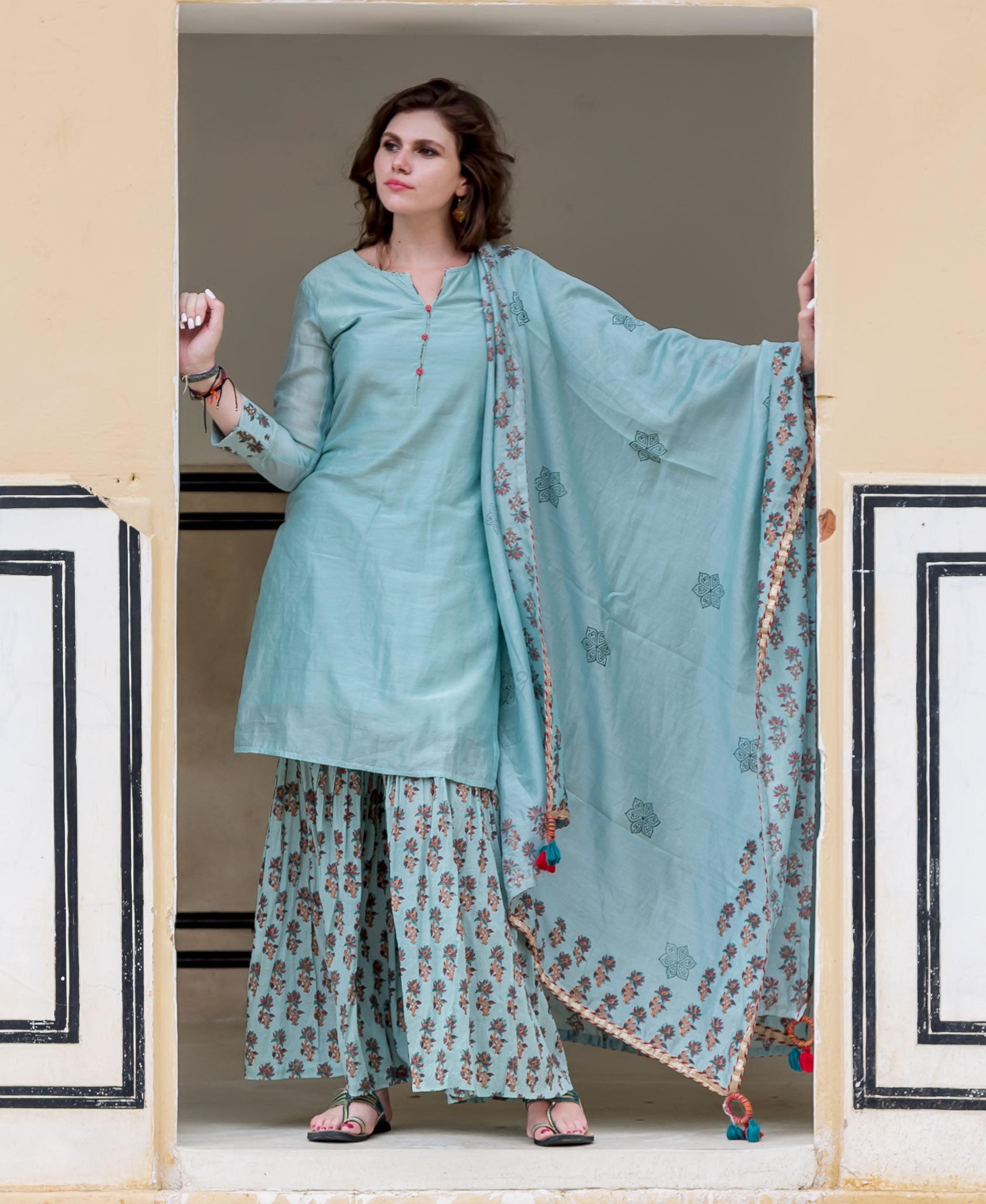 Full-front view model in ice blue solid kurta, floral block-printed sharara and dupatta.