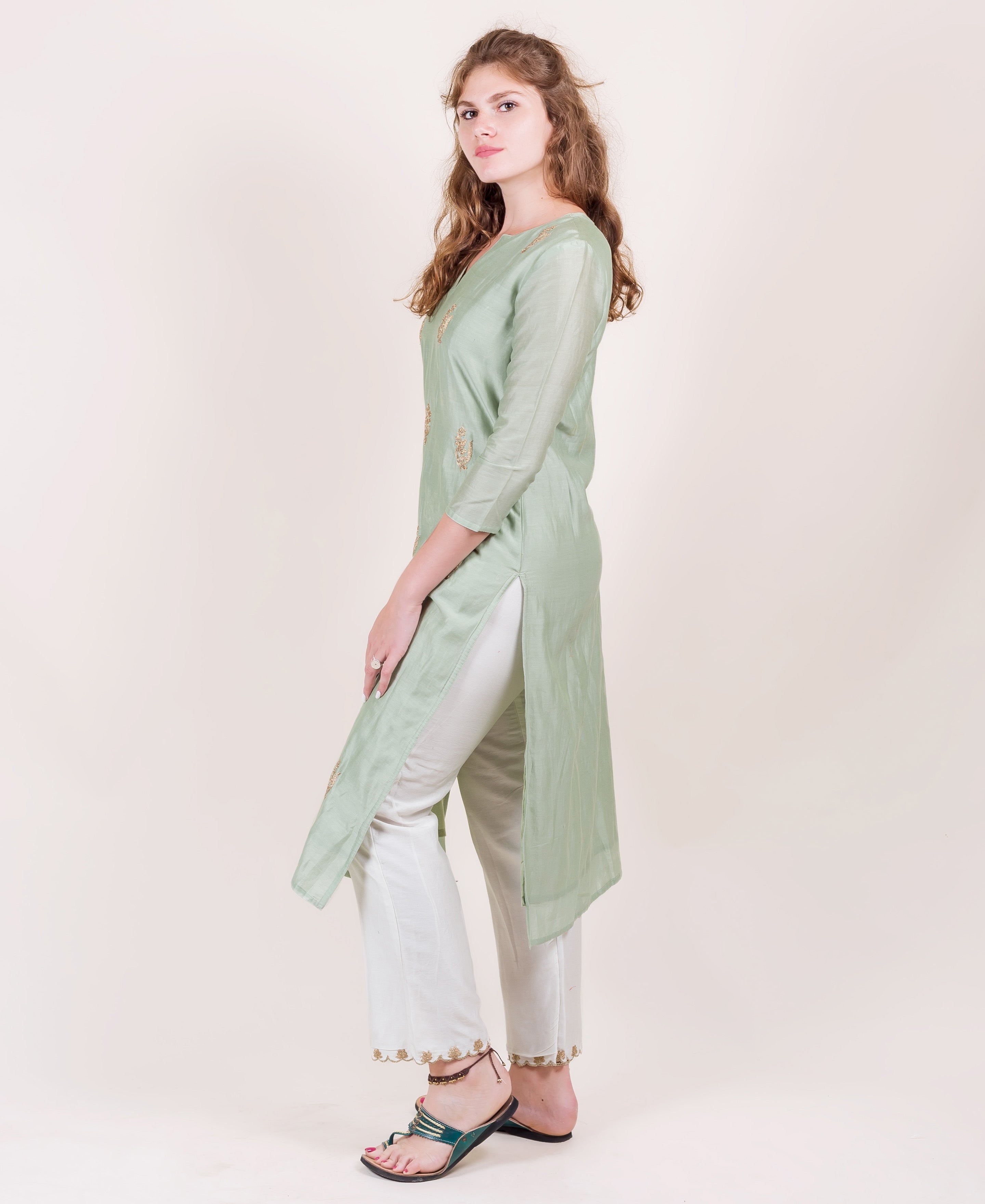 Mint green long tunic with gold accents and white pants on a female model.