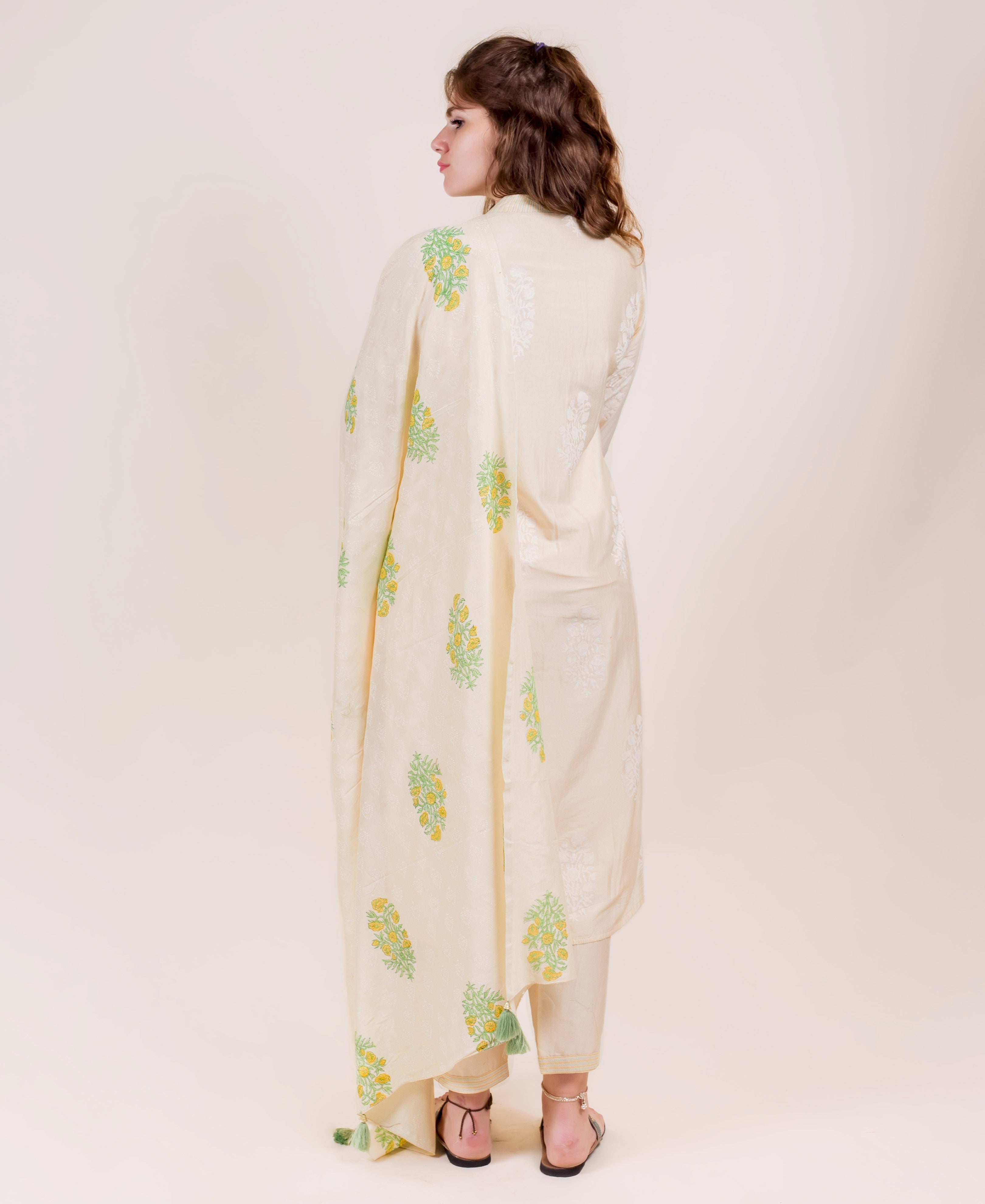 Model, back view, in pale yellow straight-cut kurta set with green yellow block print dupatta.