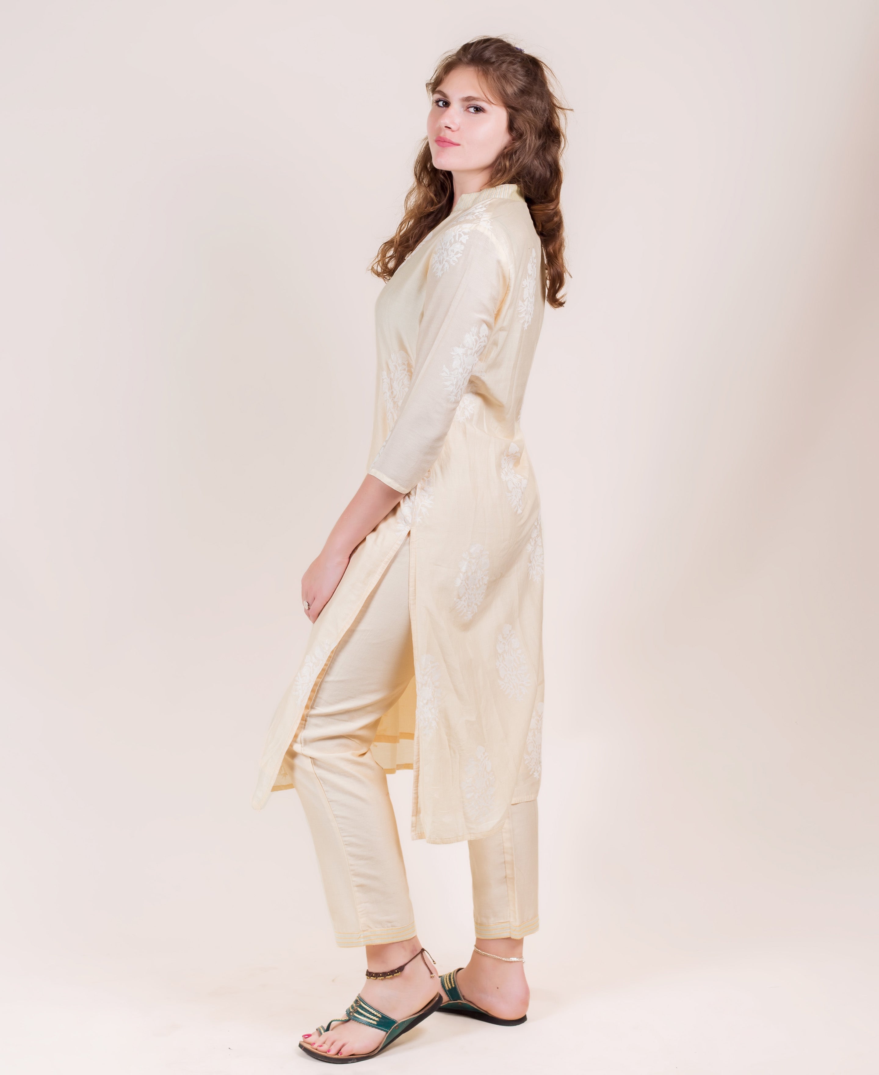 Side profile of a model wearing an off-white straight-cut kurta with white ethnic print.