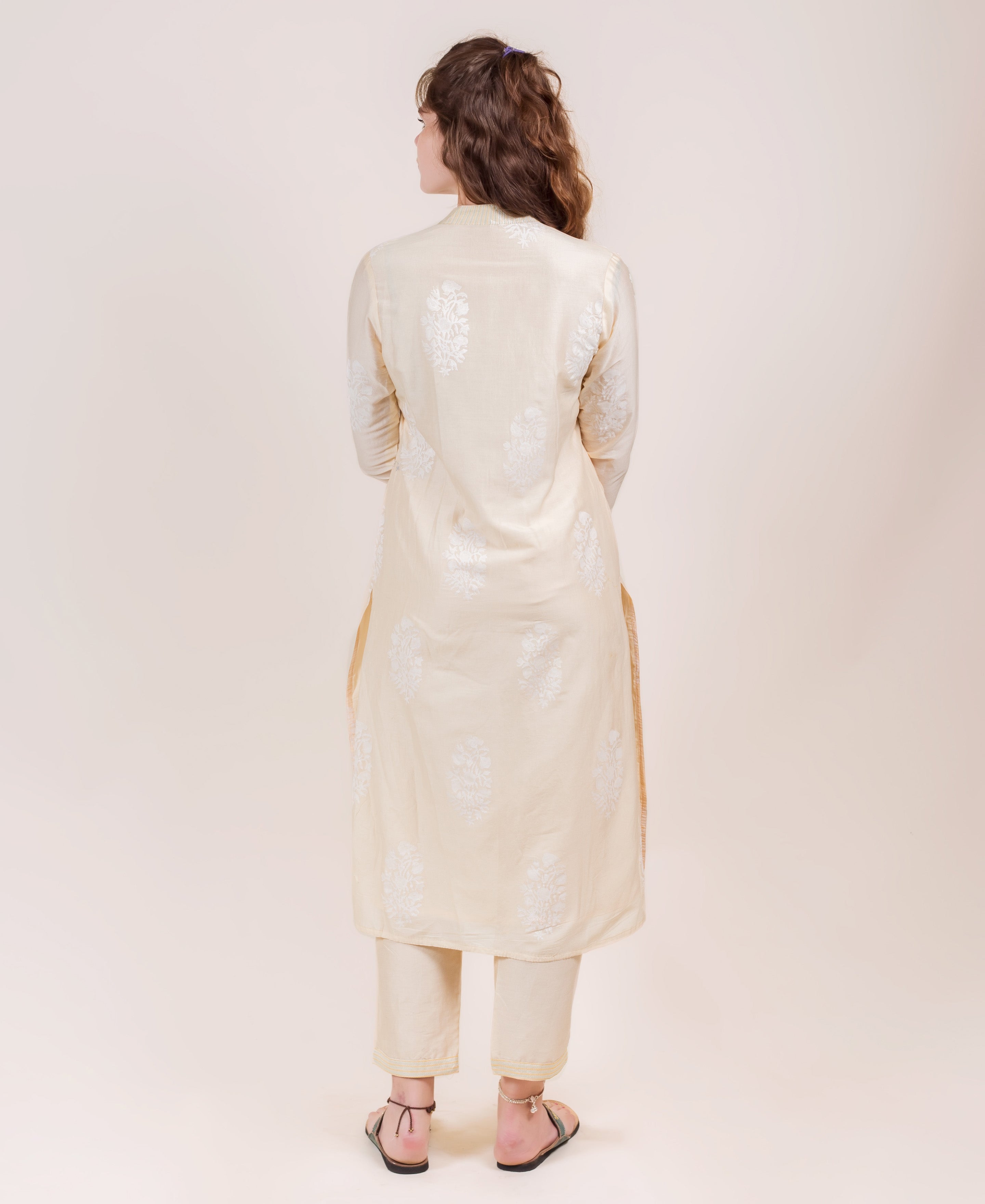 Back view of model in cream straight-cut kurta and pants with white floral block print.