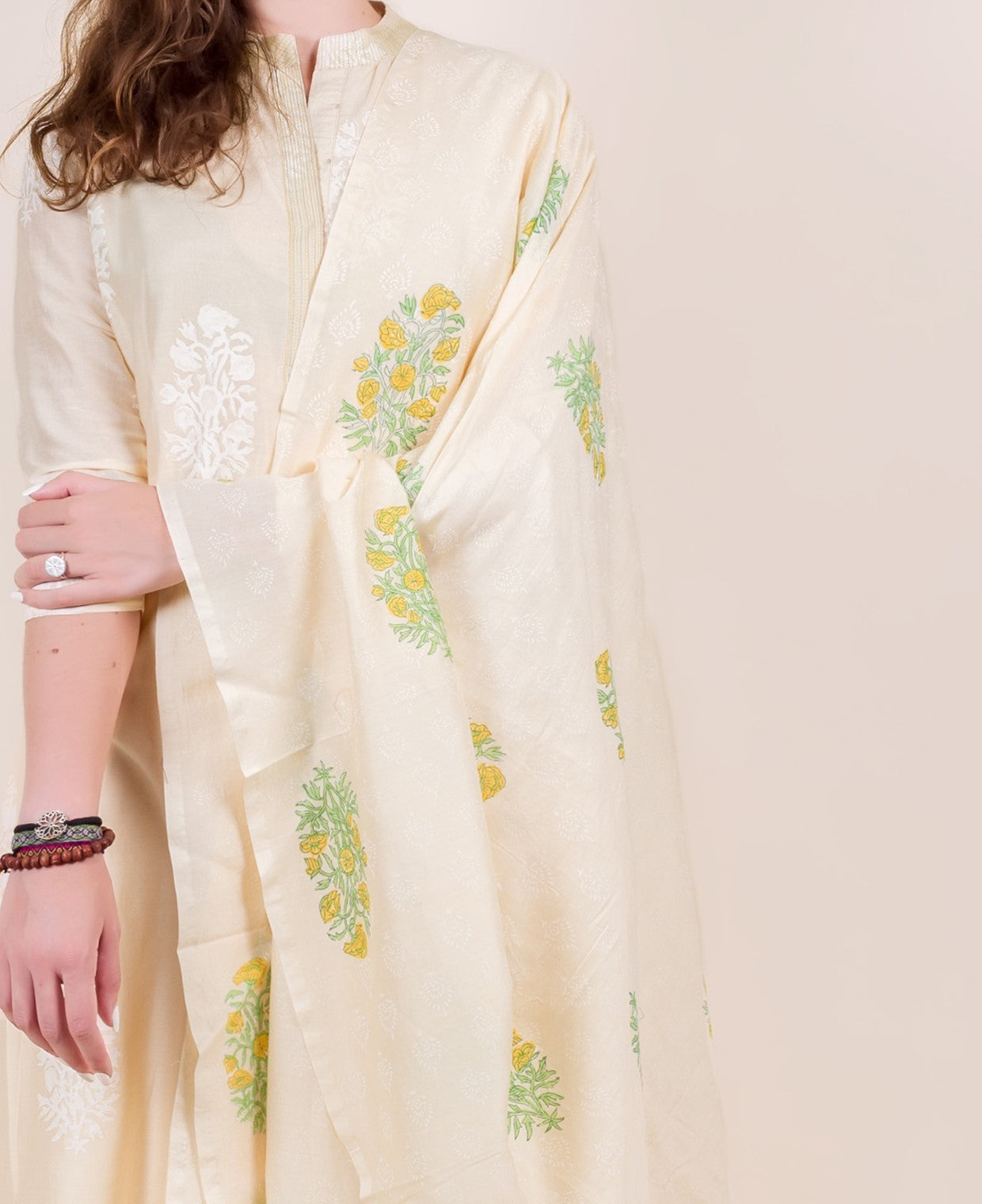 Model wears cream Chanderi kurta and dupatta with yellow and green hand-block-printed flowers.