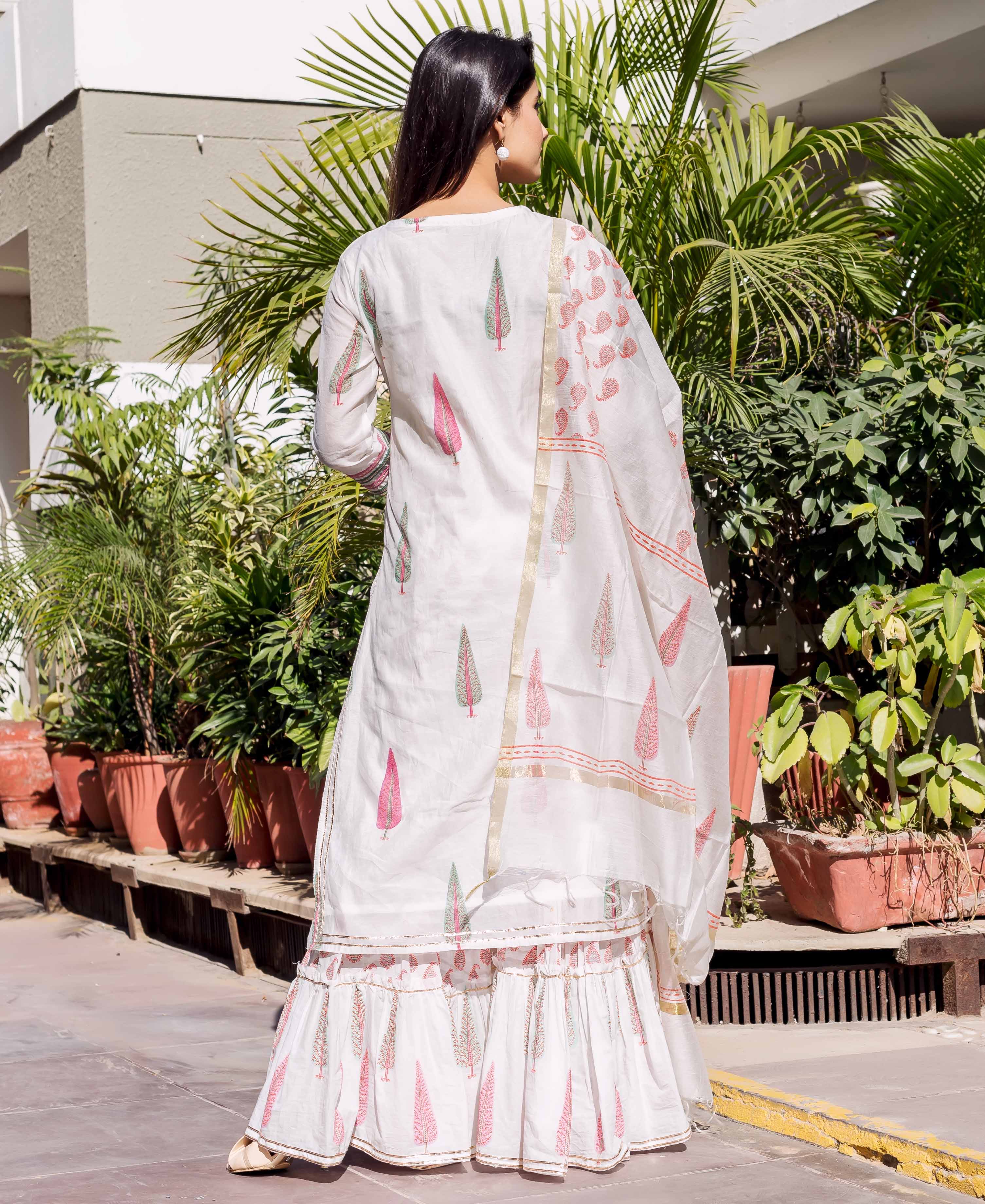 Woman in white chanderi block-printed ethnic set with pink and green leaf motifs.
