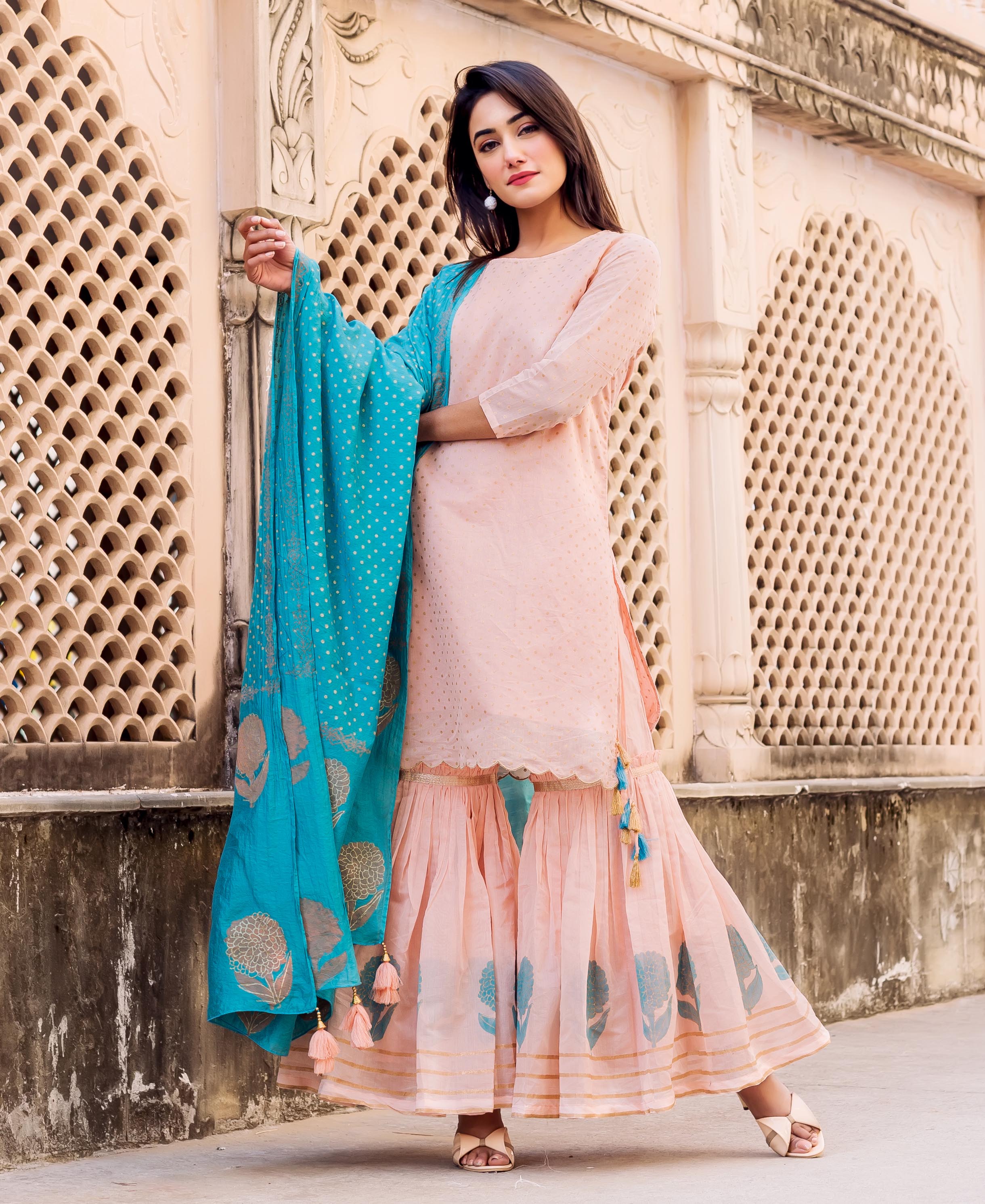 Model in peach polka printed kurta, flowy floral hand-block printed sharara, and teal dupatta.