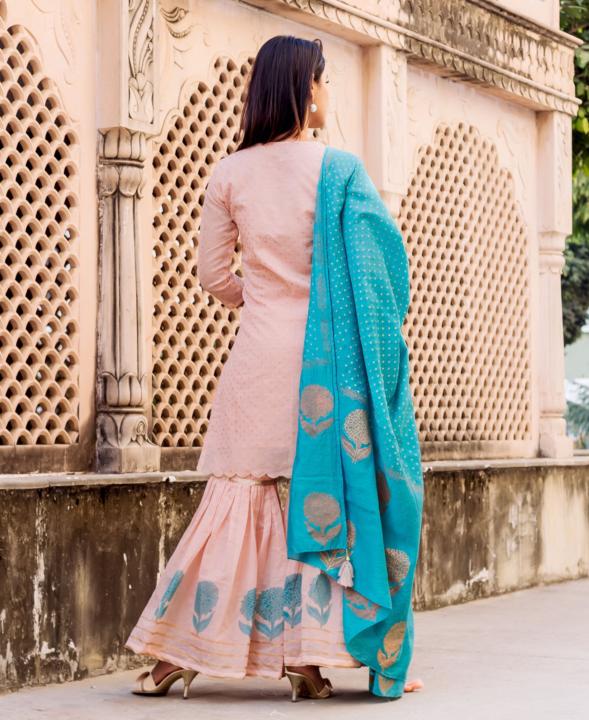 Model from behind in peach polka dot kurta, blue hand-block-printed sharara and matching dupatta.