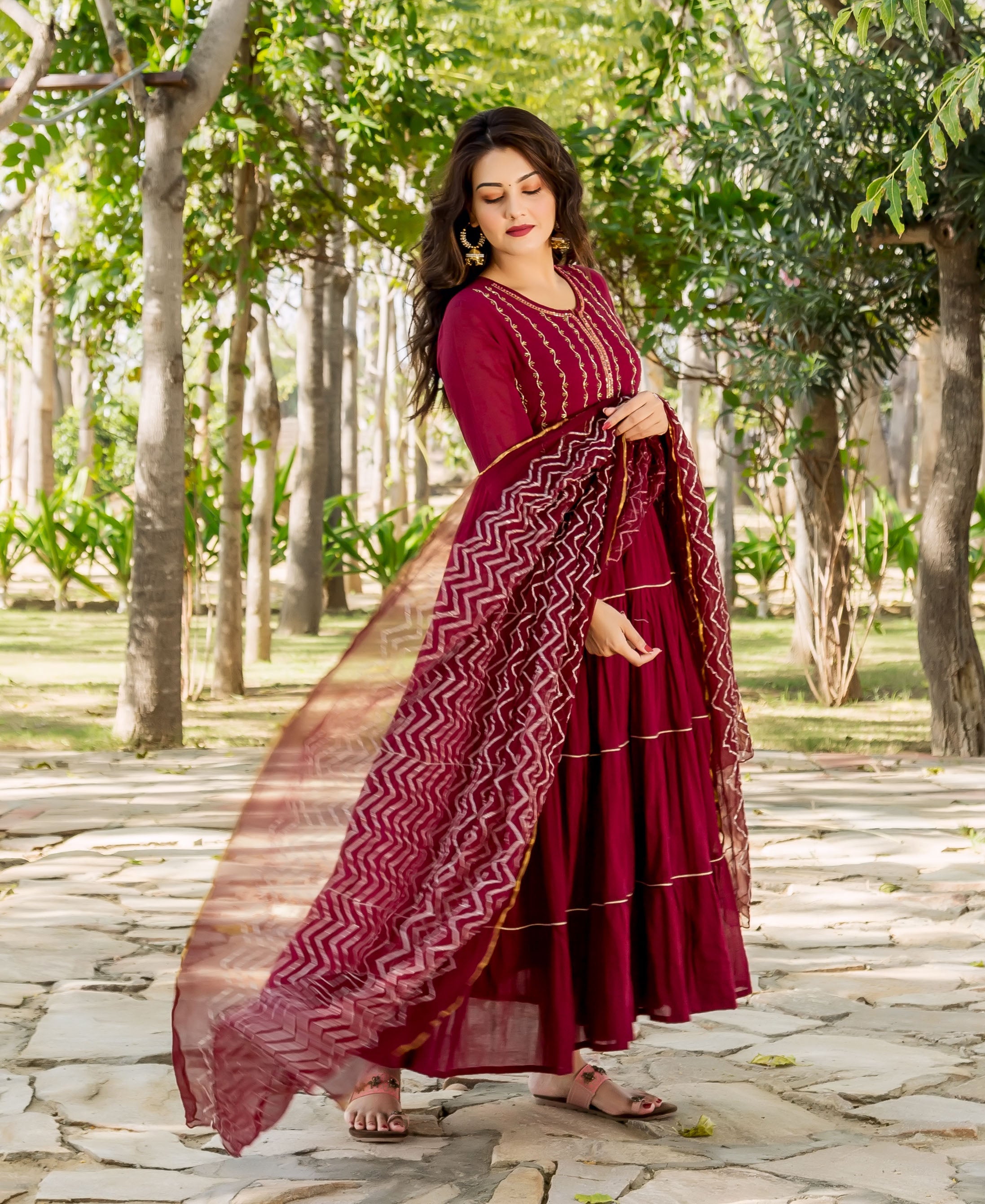 Maroon tiered dress on a model, featuring golden embroidery and a zigzag block-printed dupatta.