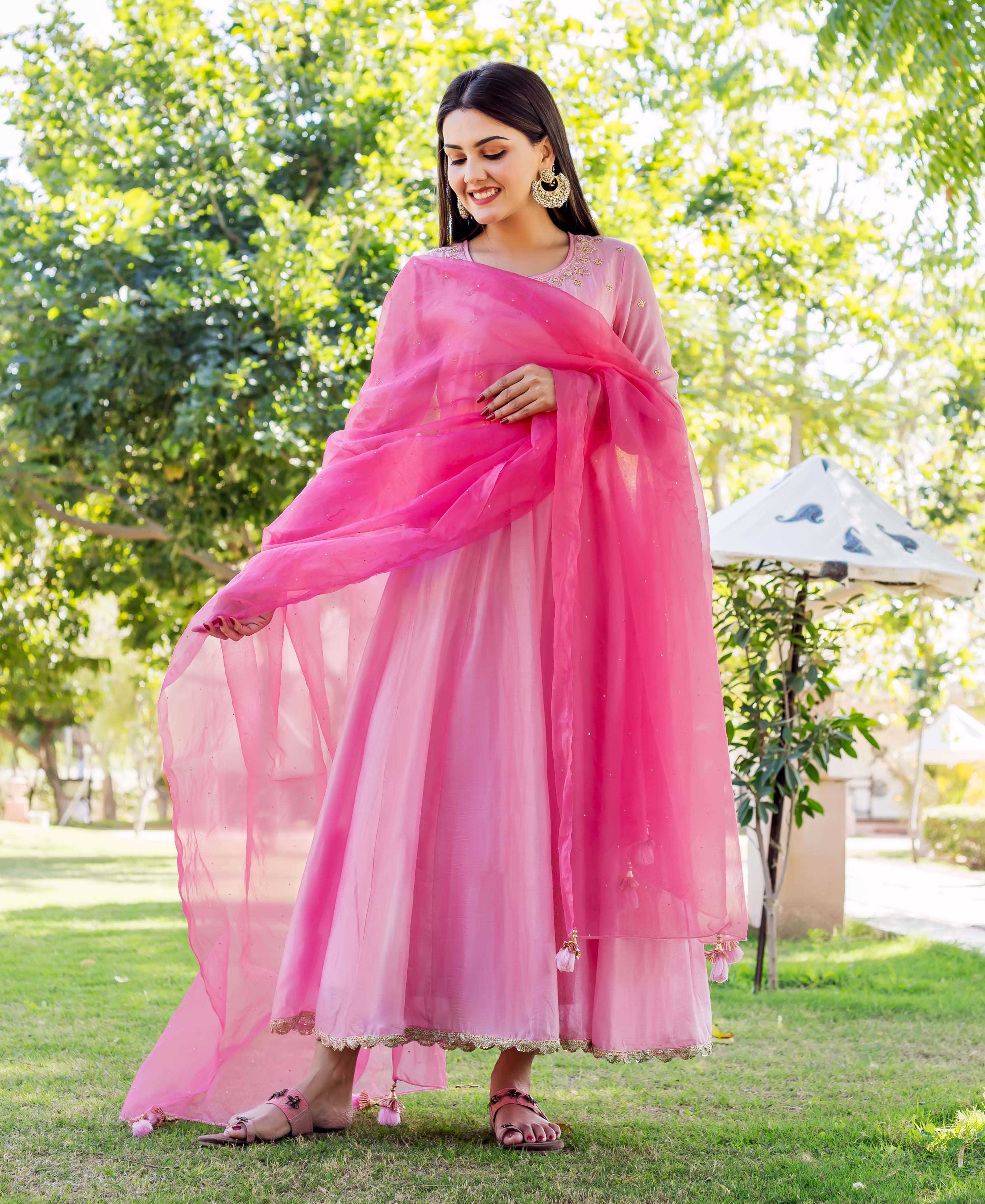 Model wears a blush pink embroidered dress with a long, flowing bright pink sheer dupatta.