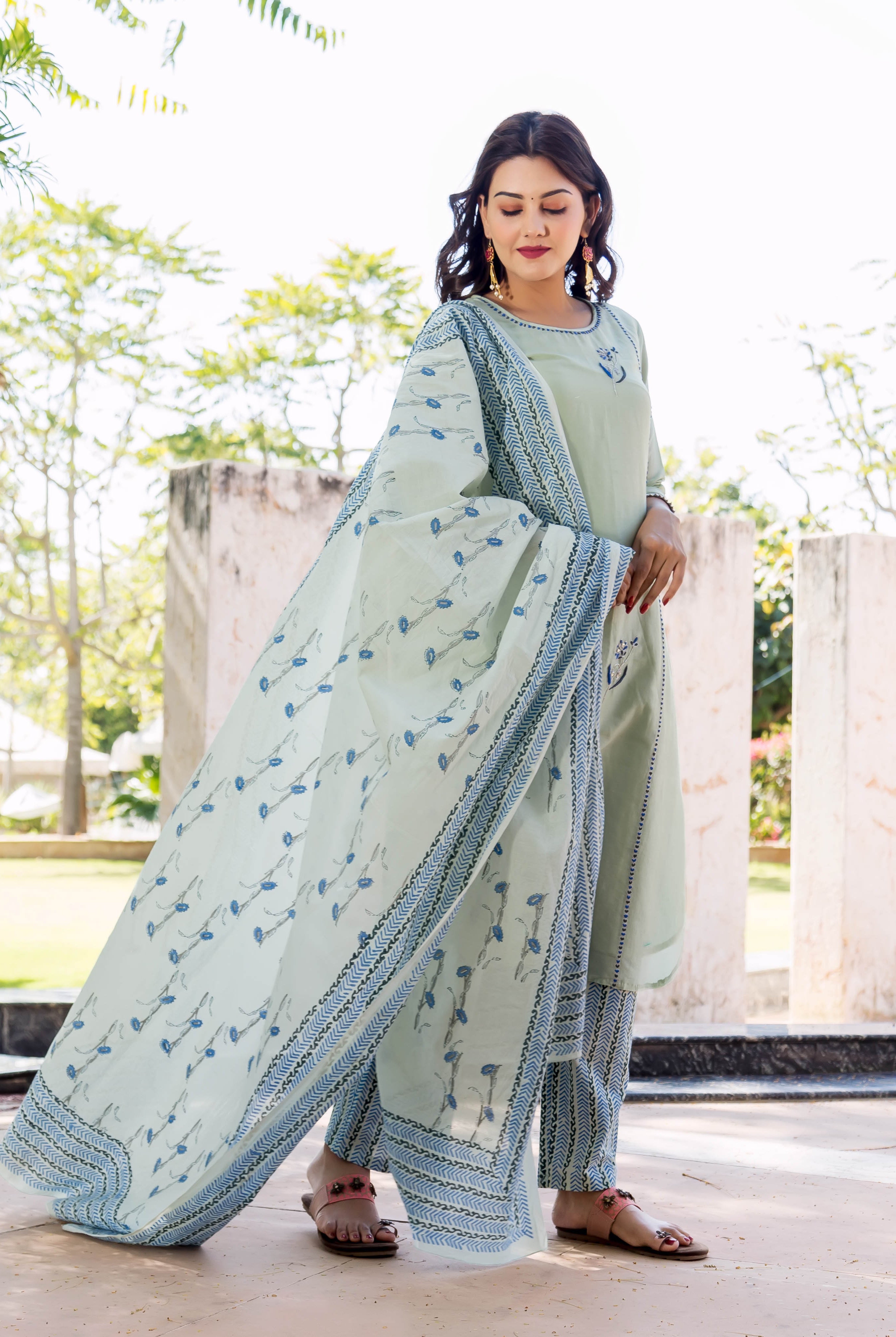 Model wears pistachio kurta set with blue hand-block printed patterns and delicate embroidery.