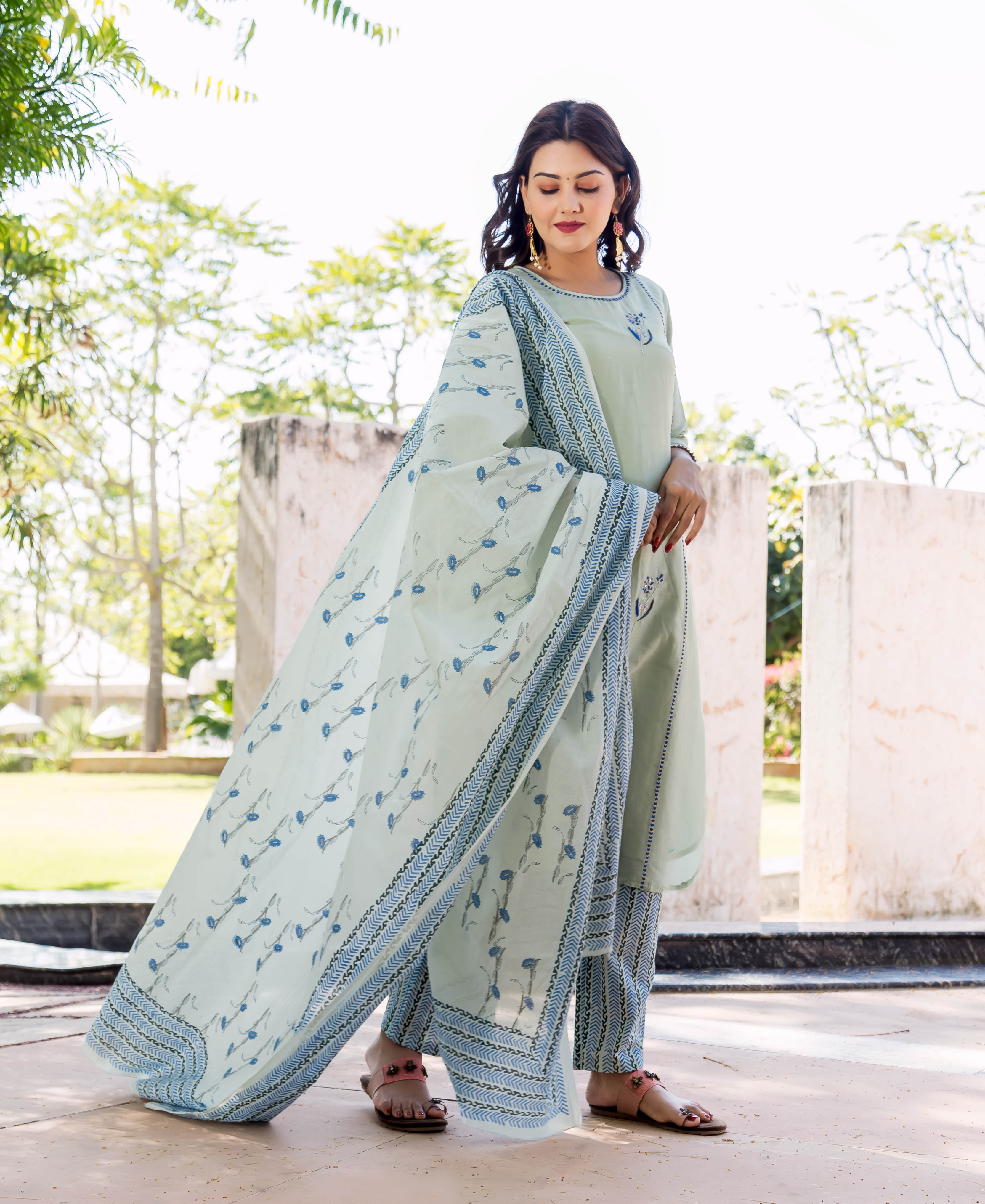 Model wears pistachio kurta set with blue hand-block printed patterns and delicate embroidery.