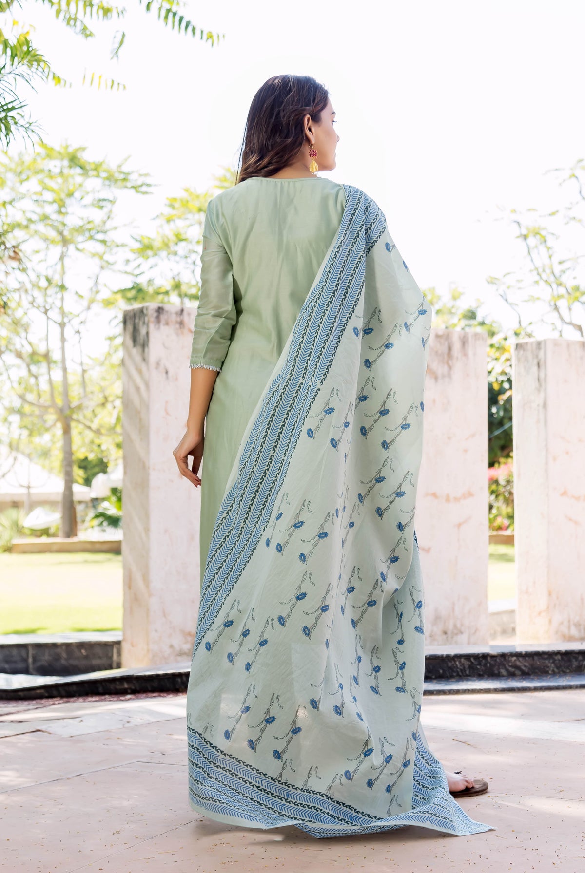 Woman wearing pistachio green kurta with a blue hand-block printed dupatta, seen from back.