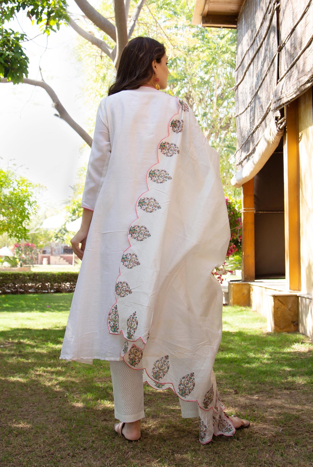 Back view of model in white kurta, scalloped dupatta with vibrant hand-embroidered ethnic patterns.