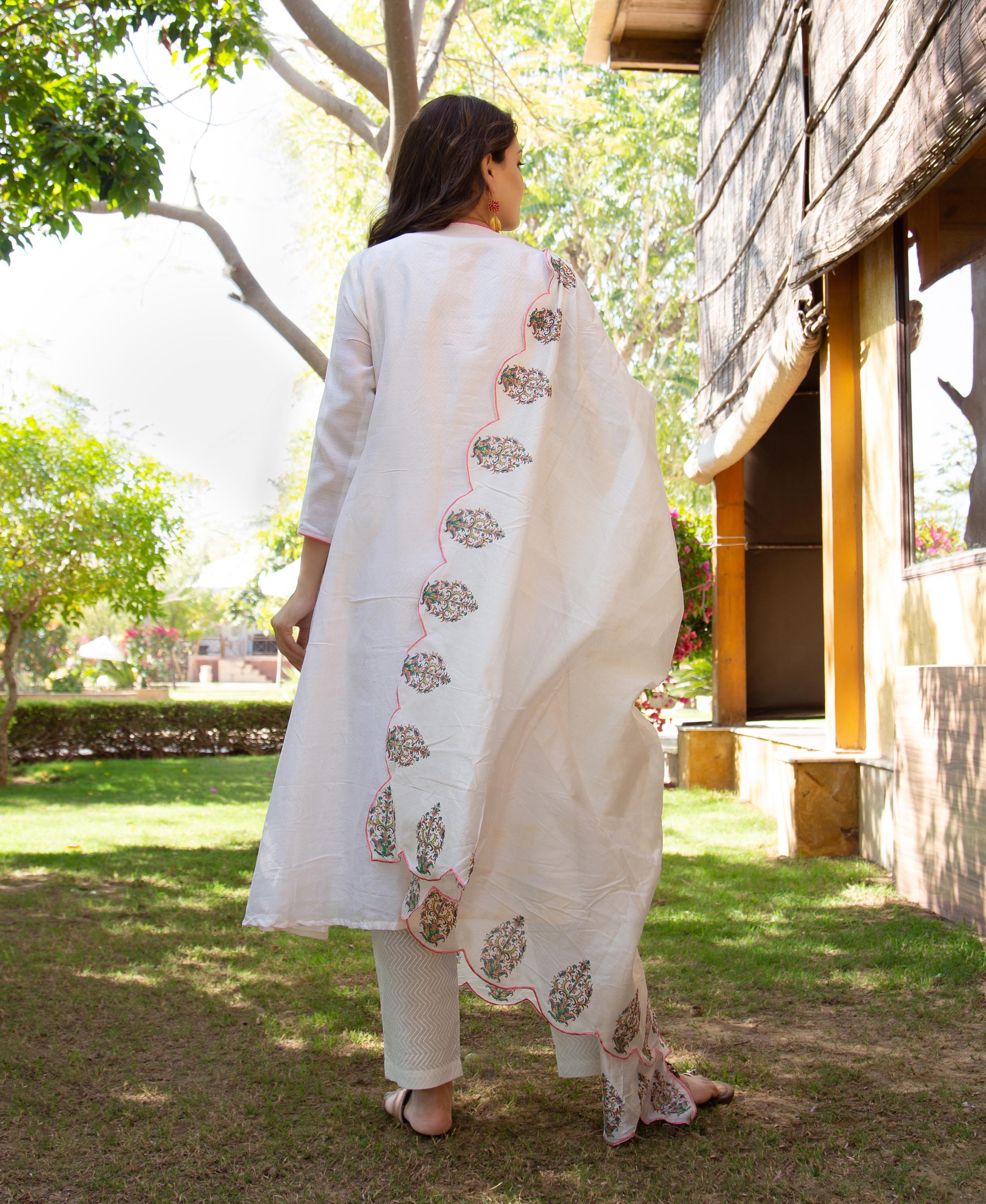 Back view of model in white kurta, scalloped dupatta with vibrant hand-embroidered ethnic patterns.