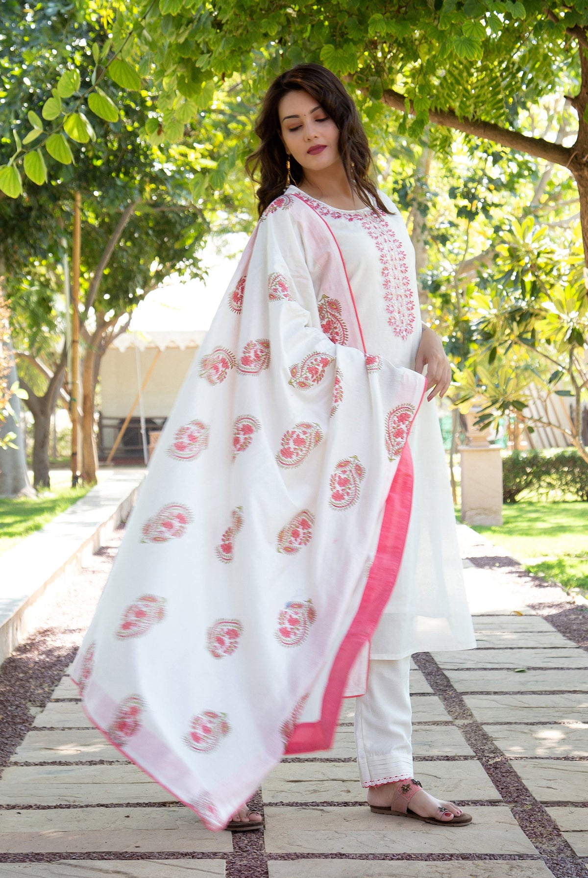 Woman models white kurta set featuring pink embroidery and a hand-block printed dupatta.