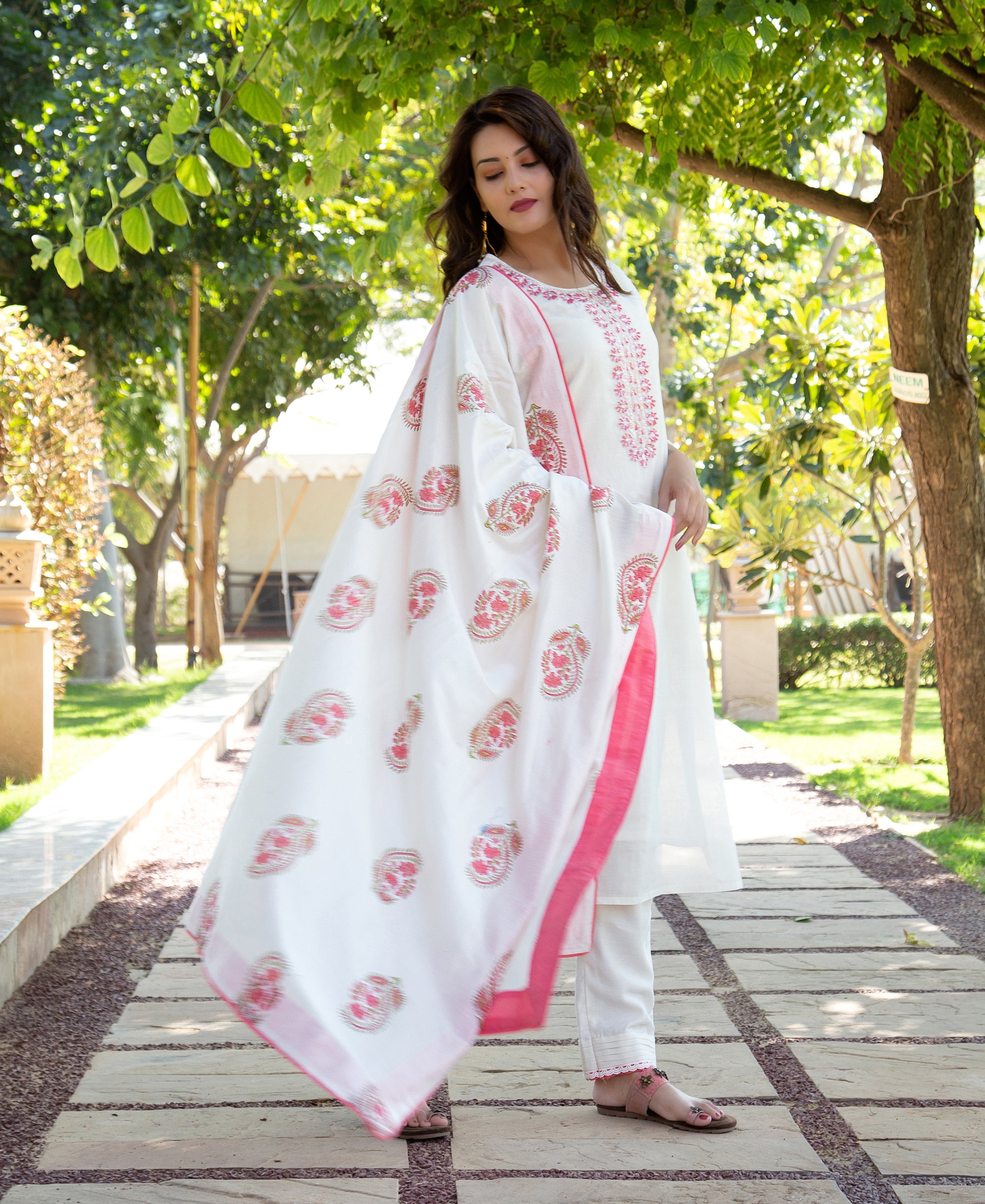 Woman models white kurta set featuring pink embroidery and a hand-block printed dupatta.