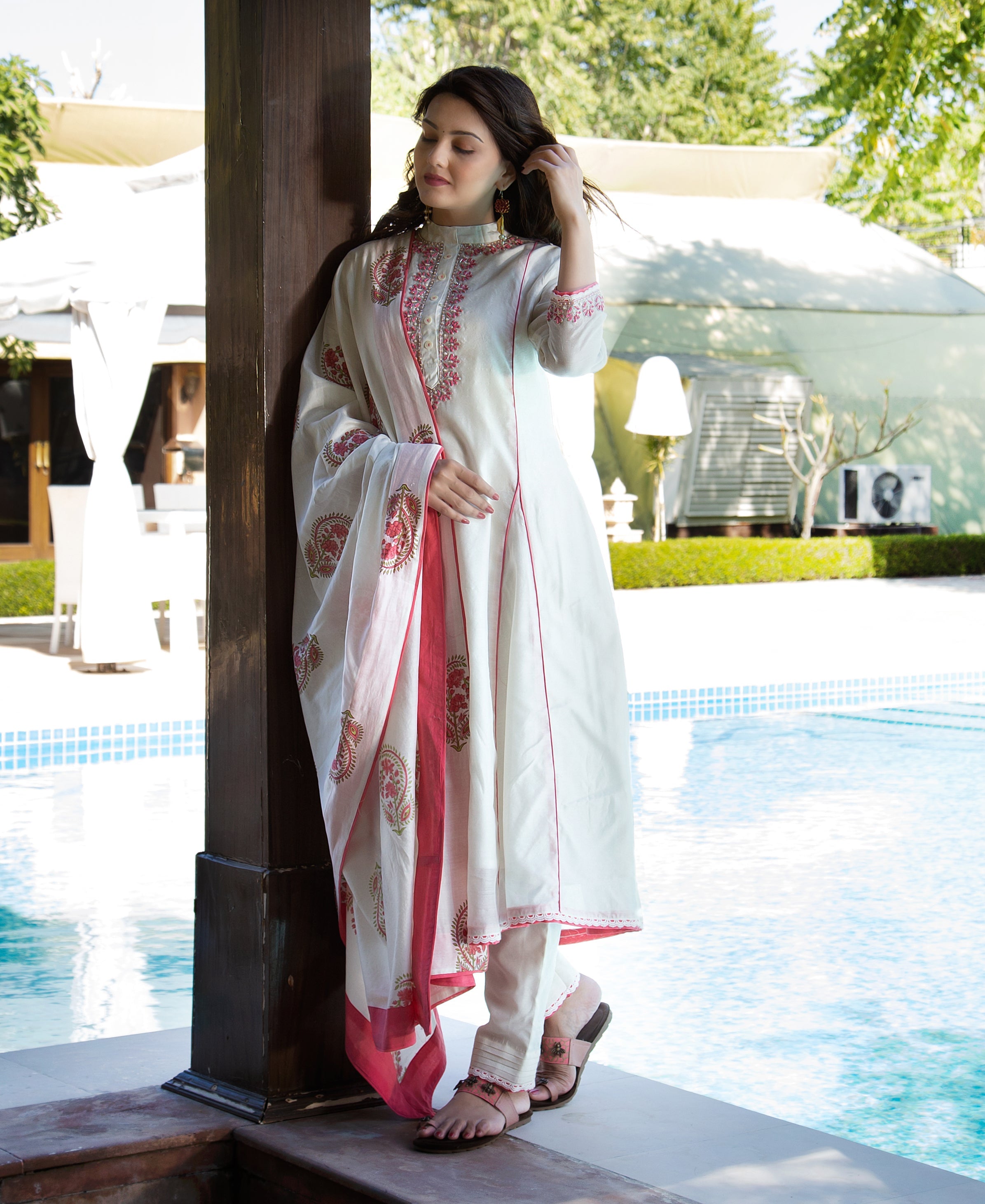 Front view of model in a white A-line kurta set with pink hand-block print and embroidery.