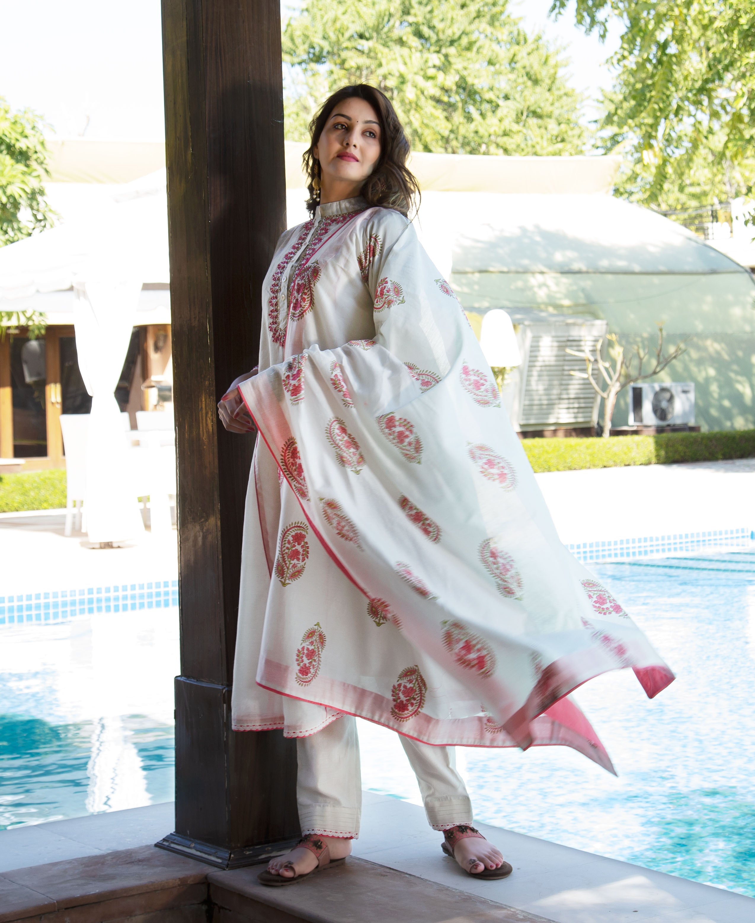 Model wears off-white hand-block-printed kurta set with vibrant red patterns, dupatta flowing.