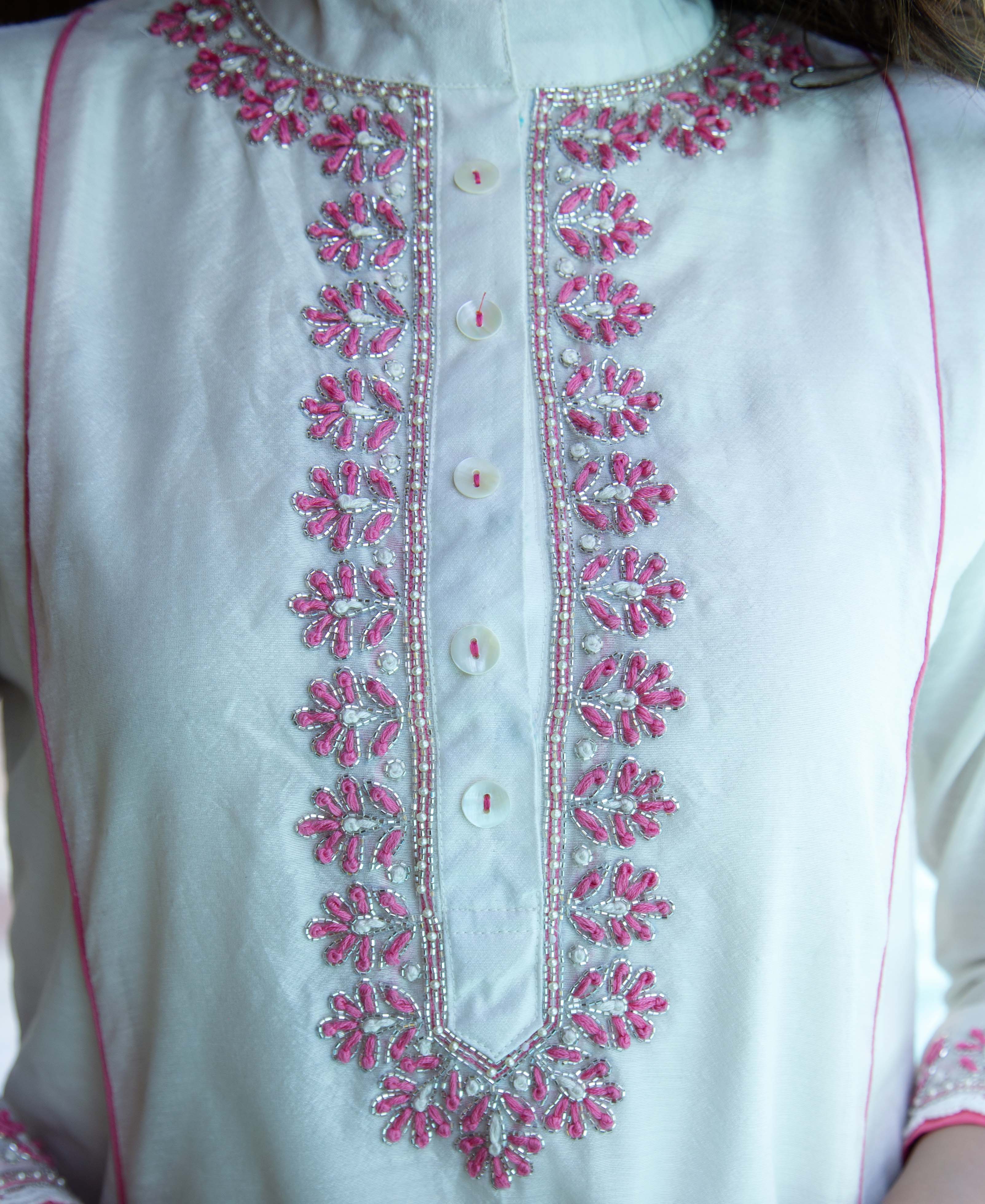 Model wears white A-line kurta with intricate pink and silver bead embroidery on the placket.
