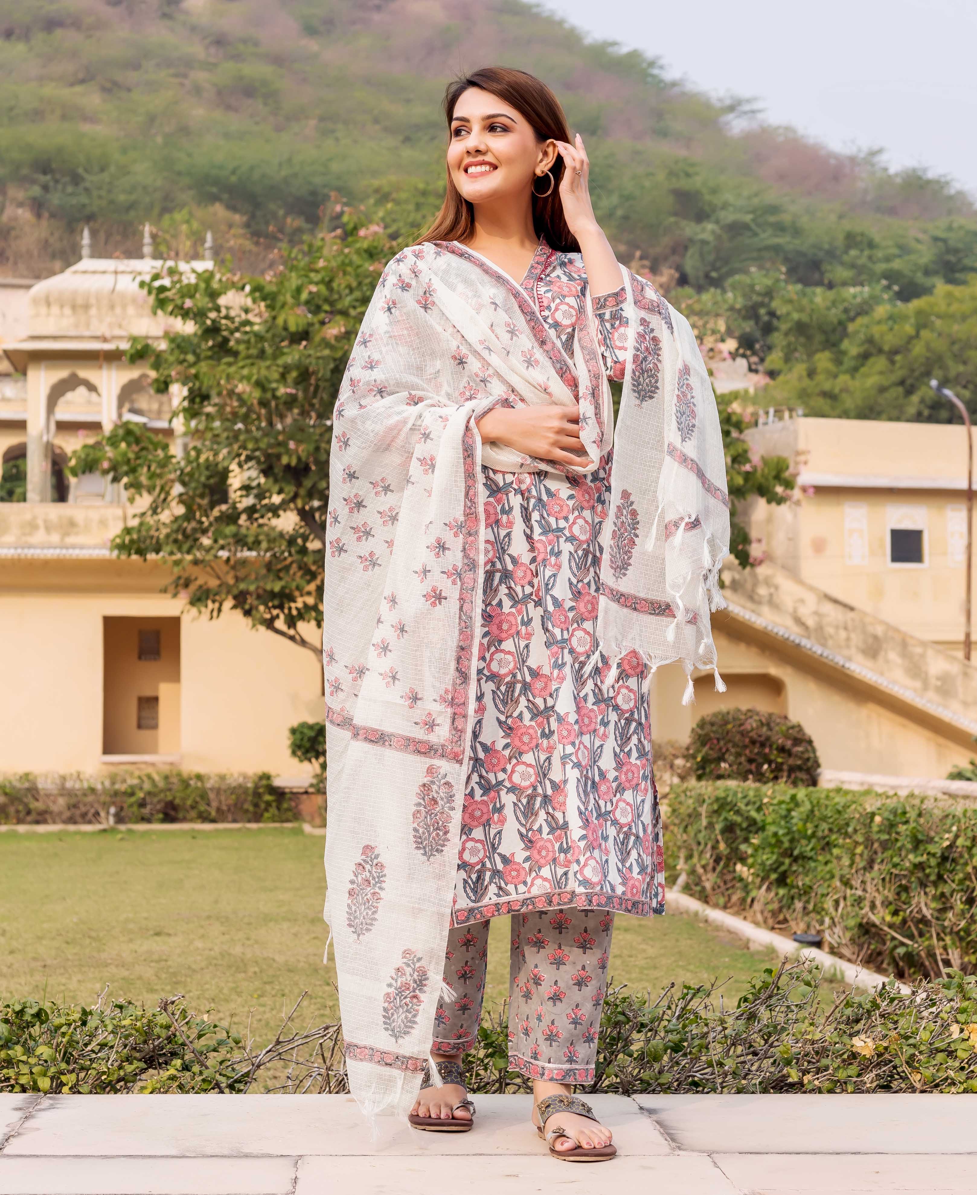 White, pink, and grey hand-block printed floral kurta set on a smiling woman.